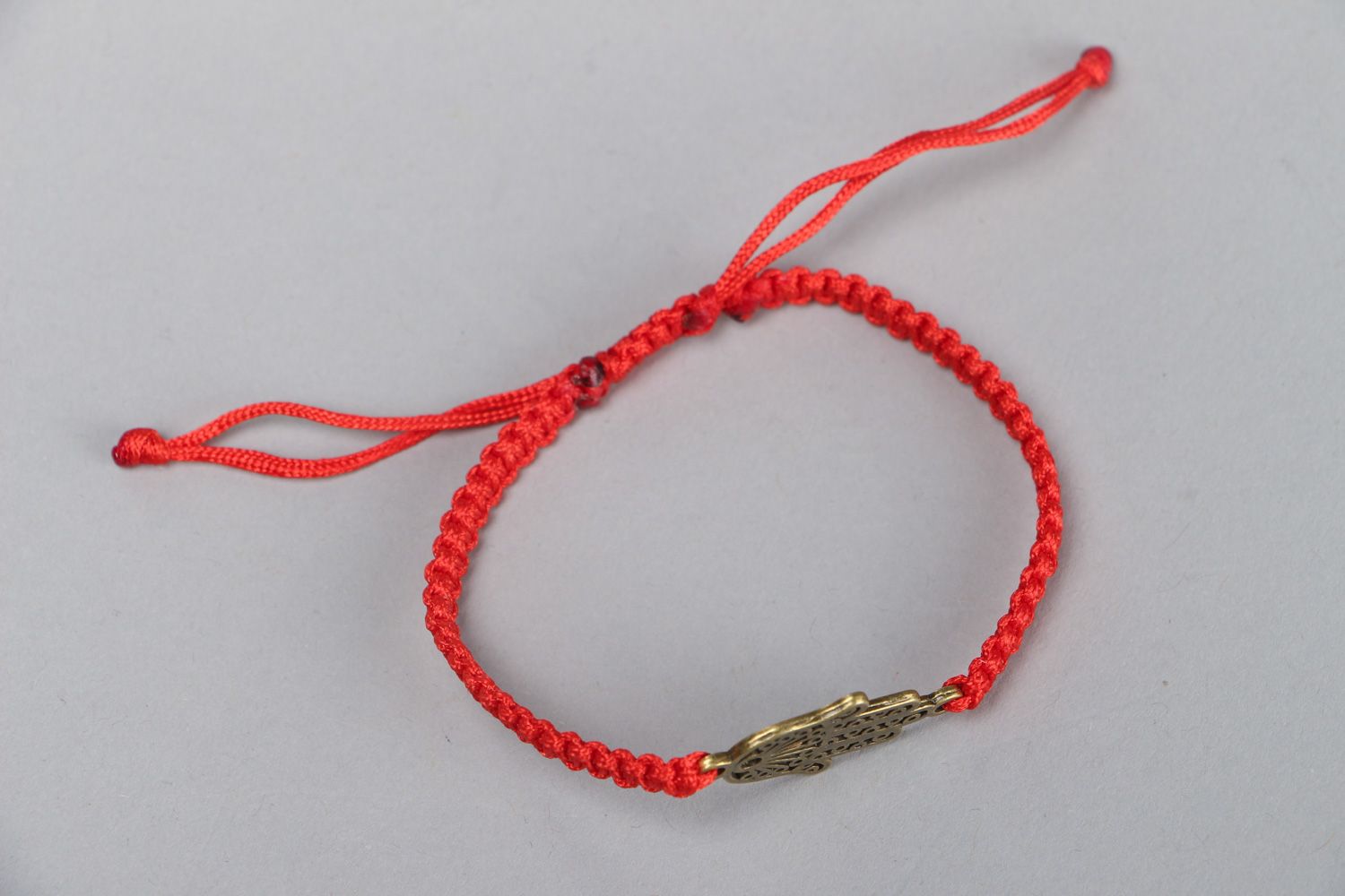 Thin handmade wrist friendship bracelet of red color with metal charm unisex photo 1