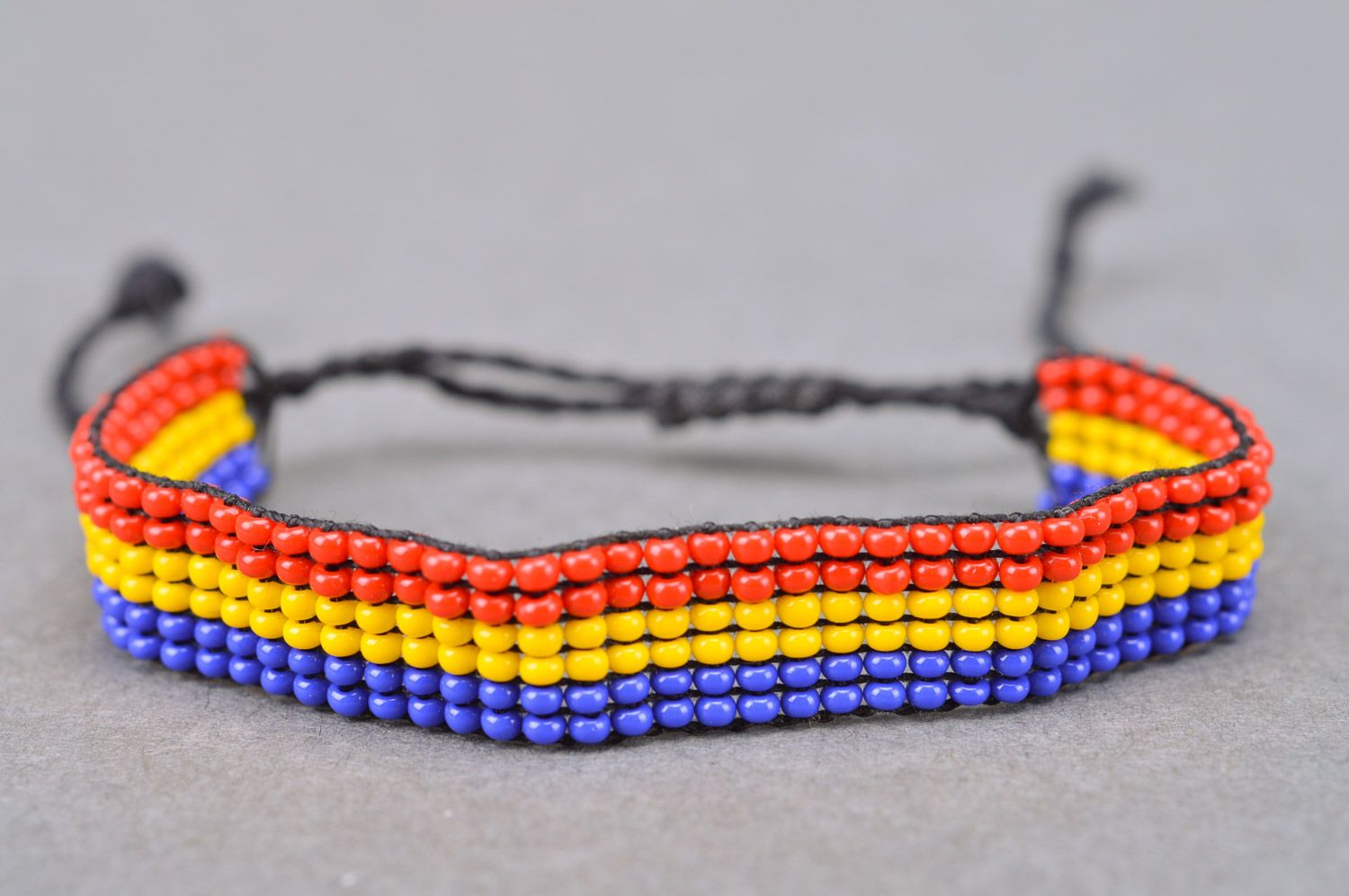 Beautiful stylish handmade women's wrist bracelet woven of three-colored beads and threads photo 2
