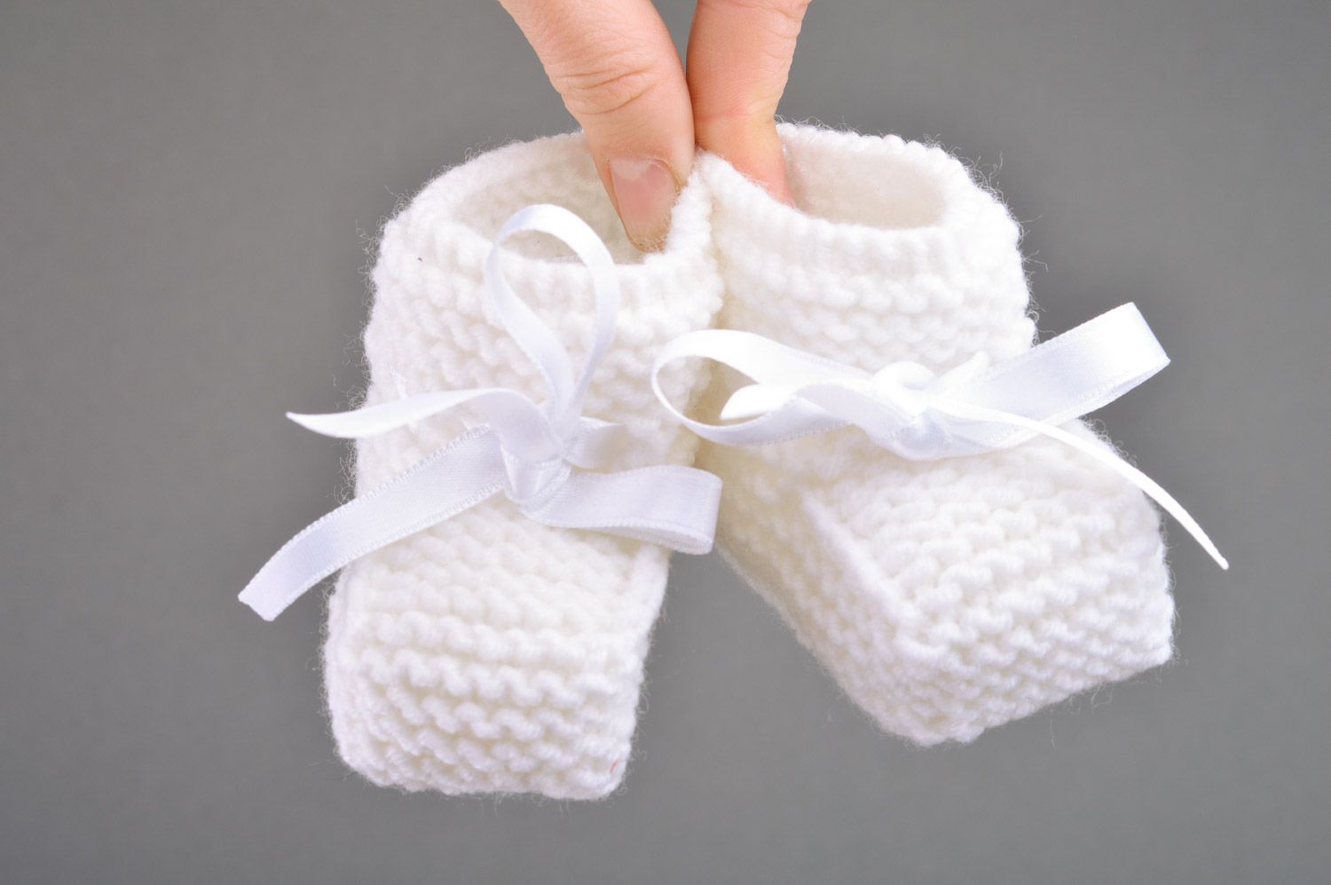 Handmade small knitted baby booties of white color with satin bow for girls photo 3