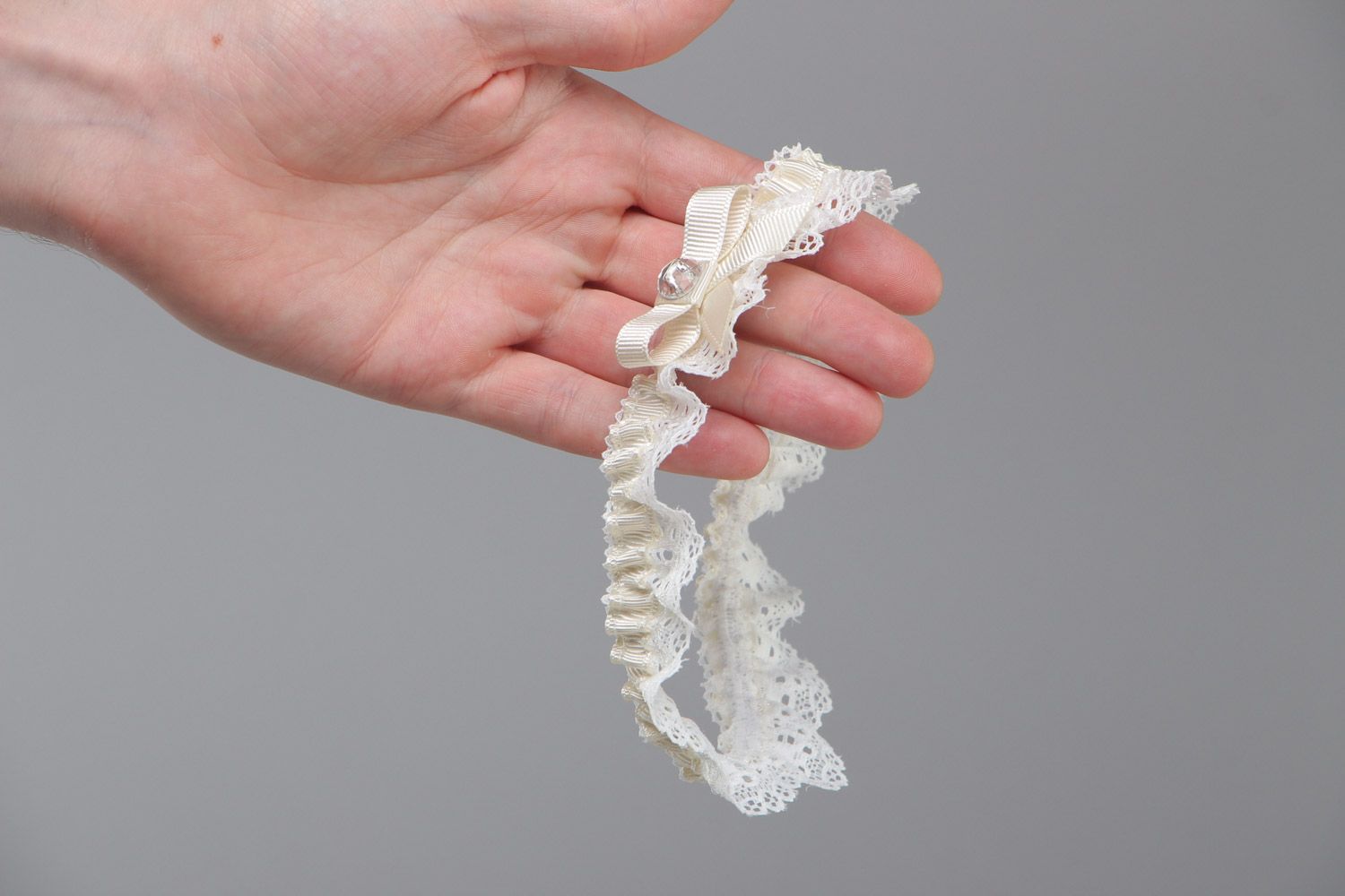 Handgemachtes weißes Strumpfband für Hochzeit aus Spitze und Ripsbändern mit Glasperle foto 5