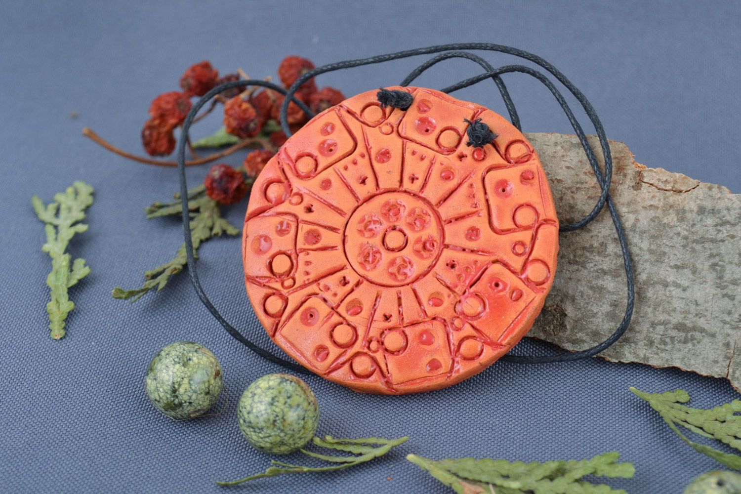 Handmade bright orange ceramic pendant of round shape with ornament on cord photo 1