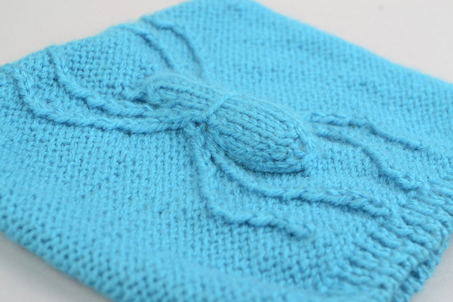Knitted warm hat made of acrylic threads with a three-dimensional pattern in the form of a blue spider photo 1