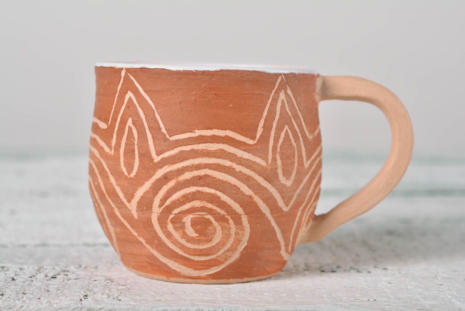 Rustic clay cup in white and brown color with handle and cave drawings photo 1