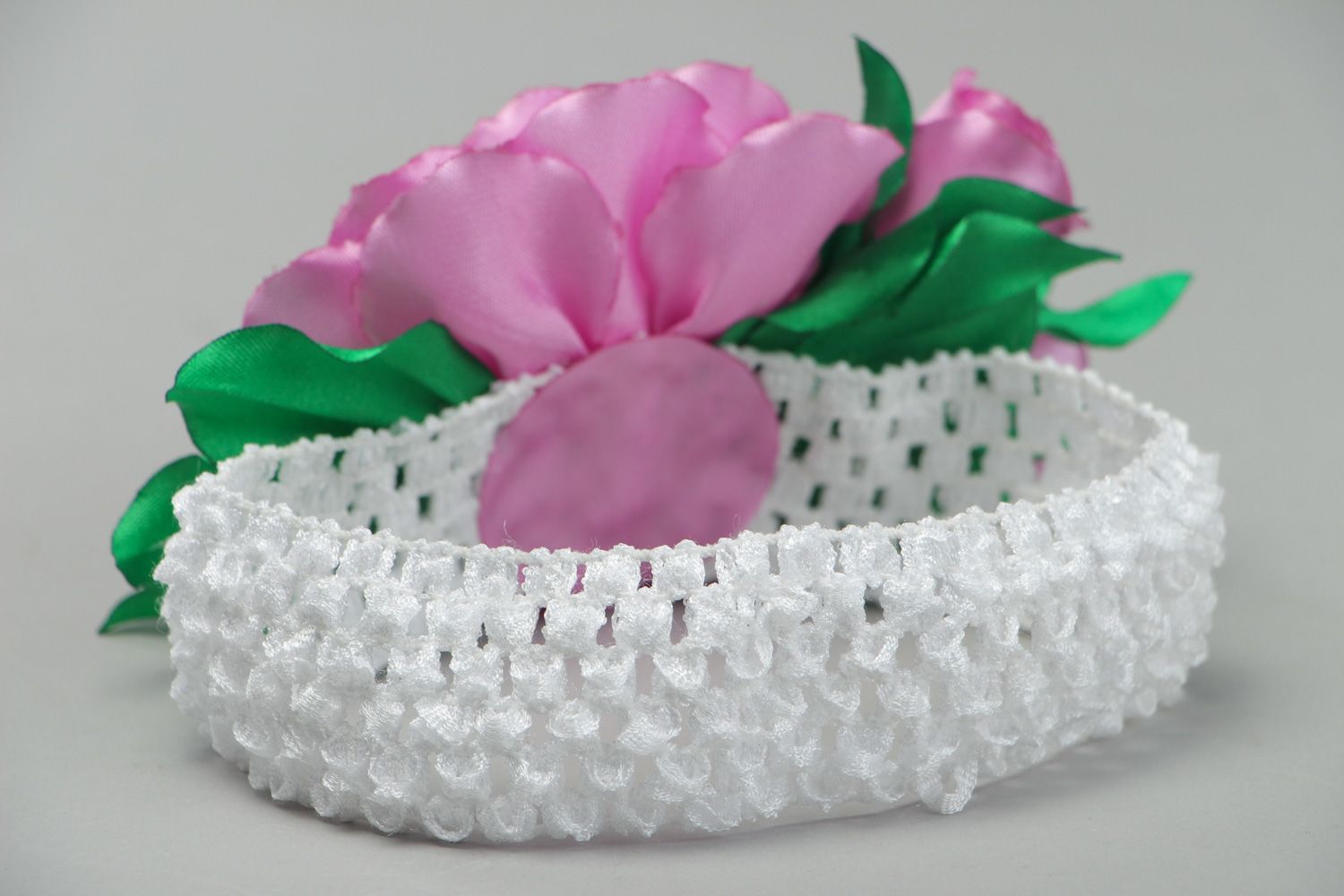 Bright elastic handmade headband with satin flower of pink color with green leaves photo 3