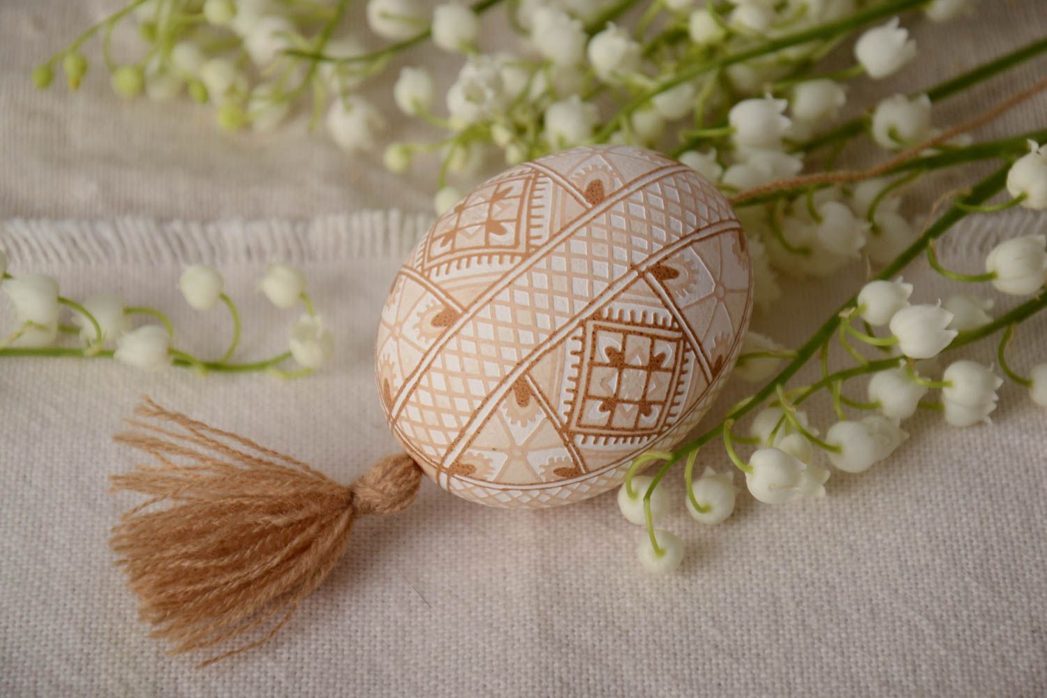 Handmade decorative light beige painted egg with geometric ornaments and tassel photo 1