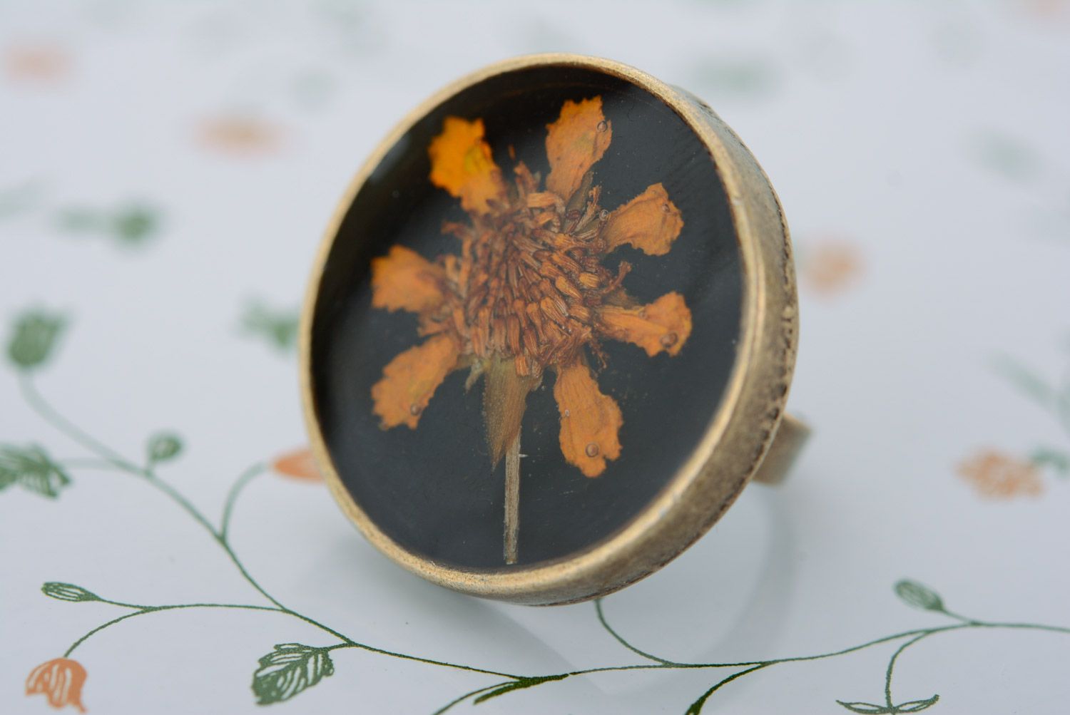 Handmade round metal ring with bright flower on black background in epoxy resin photo 3