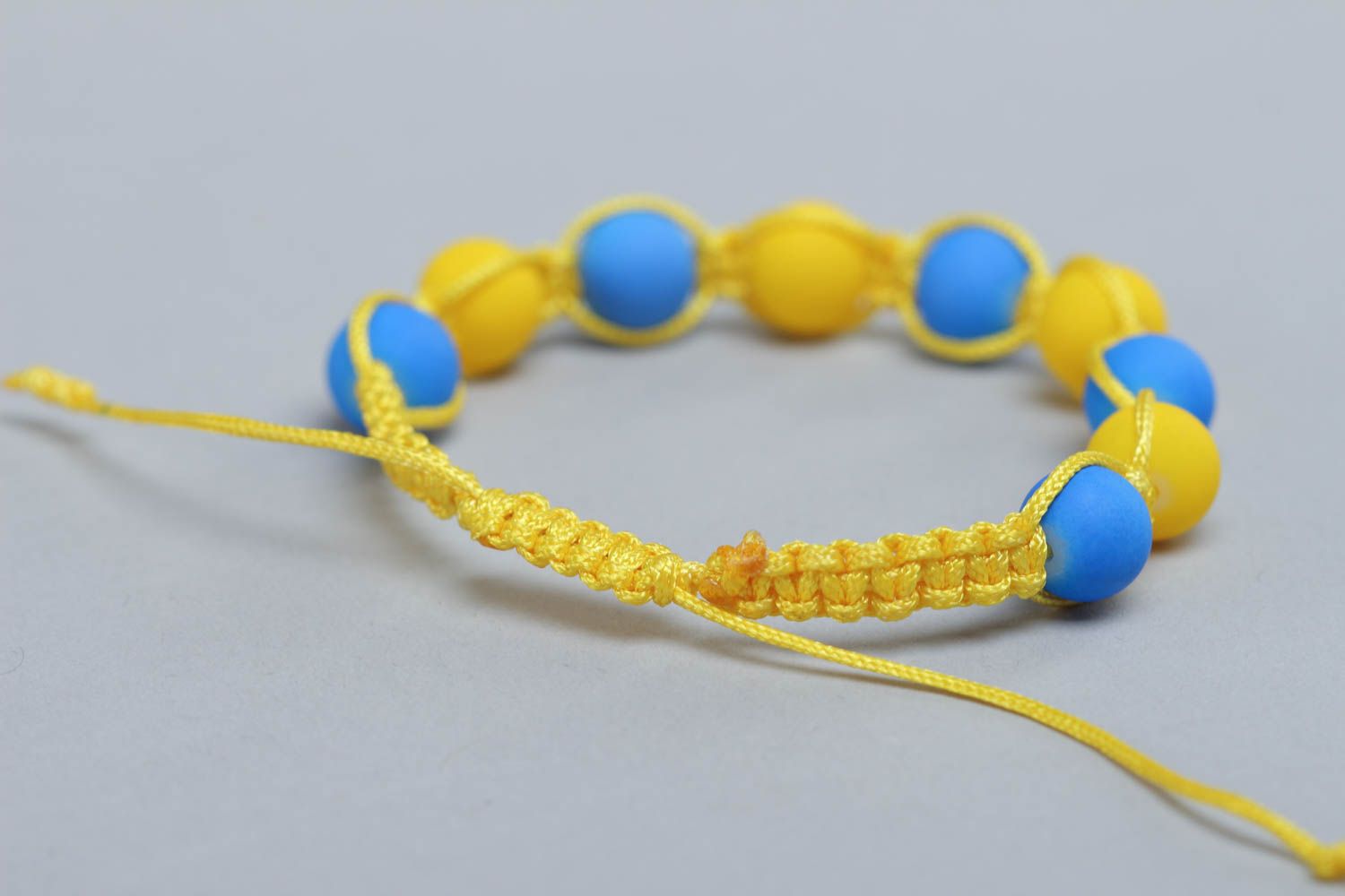 Pulsera artesanal  trenzada de hilos con cuentas plásticas azul y amarilla foto 5