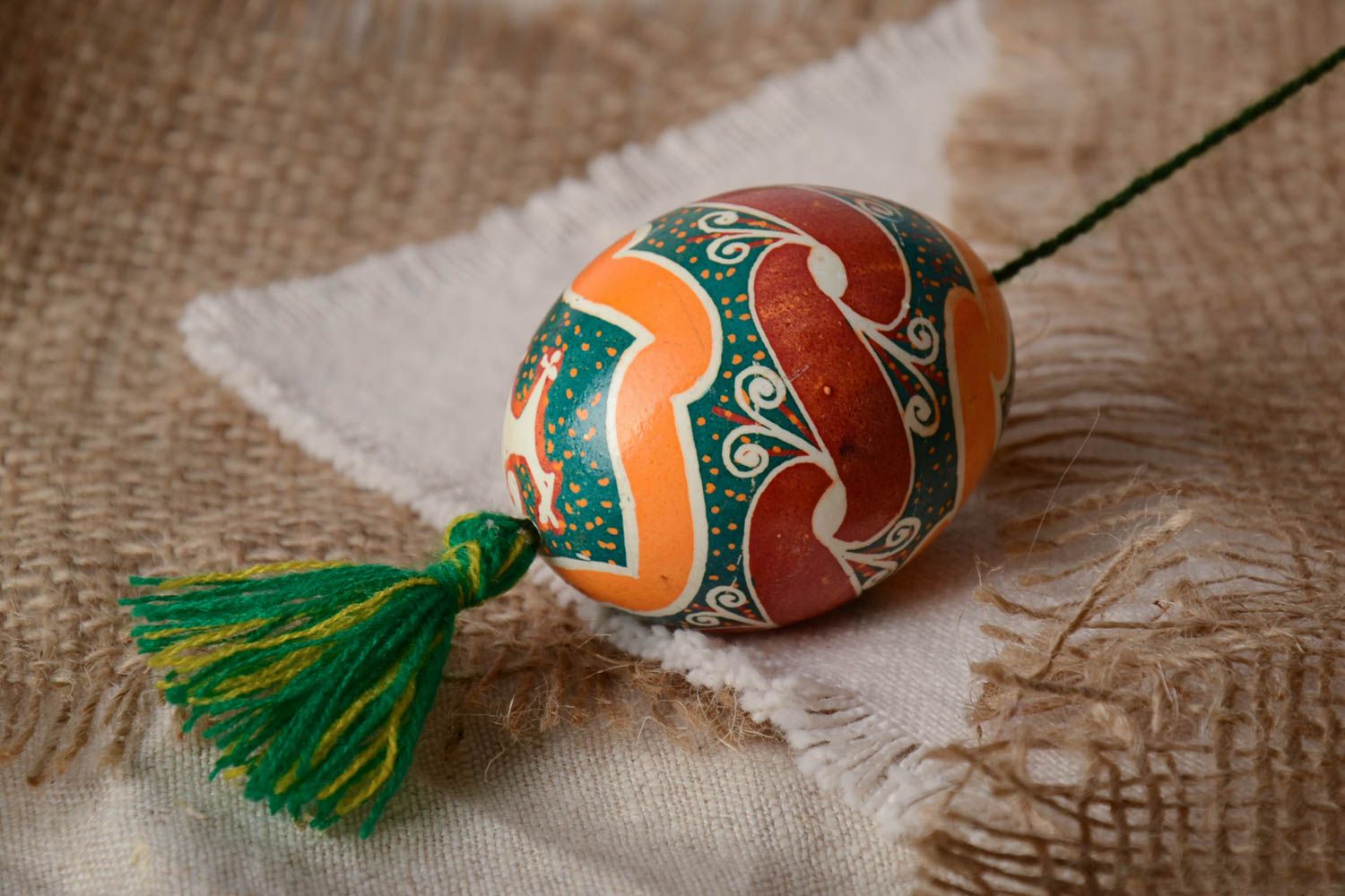 Handmade decorative colorful painted Easter egg pysanka with green tassel photo 1