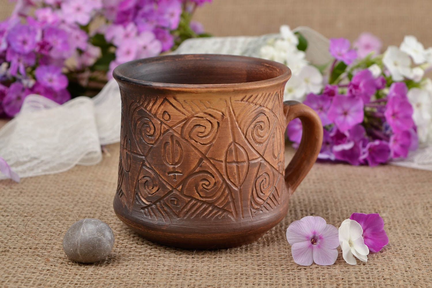 Clay cup for drinks in brown color with handle and cave symbols photo 1
