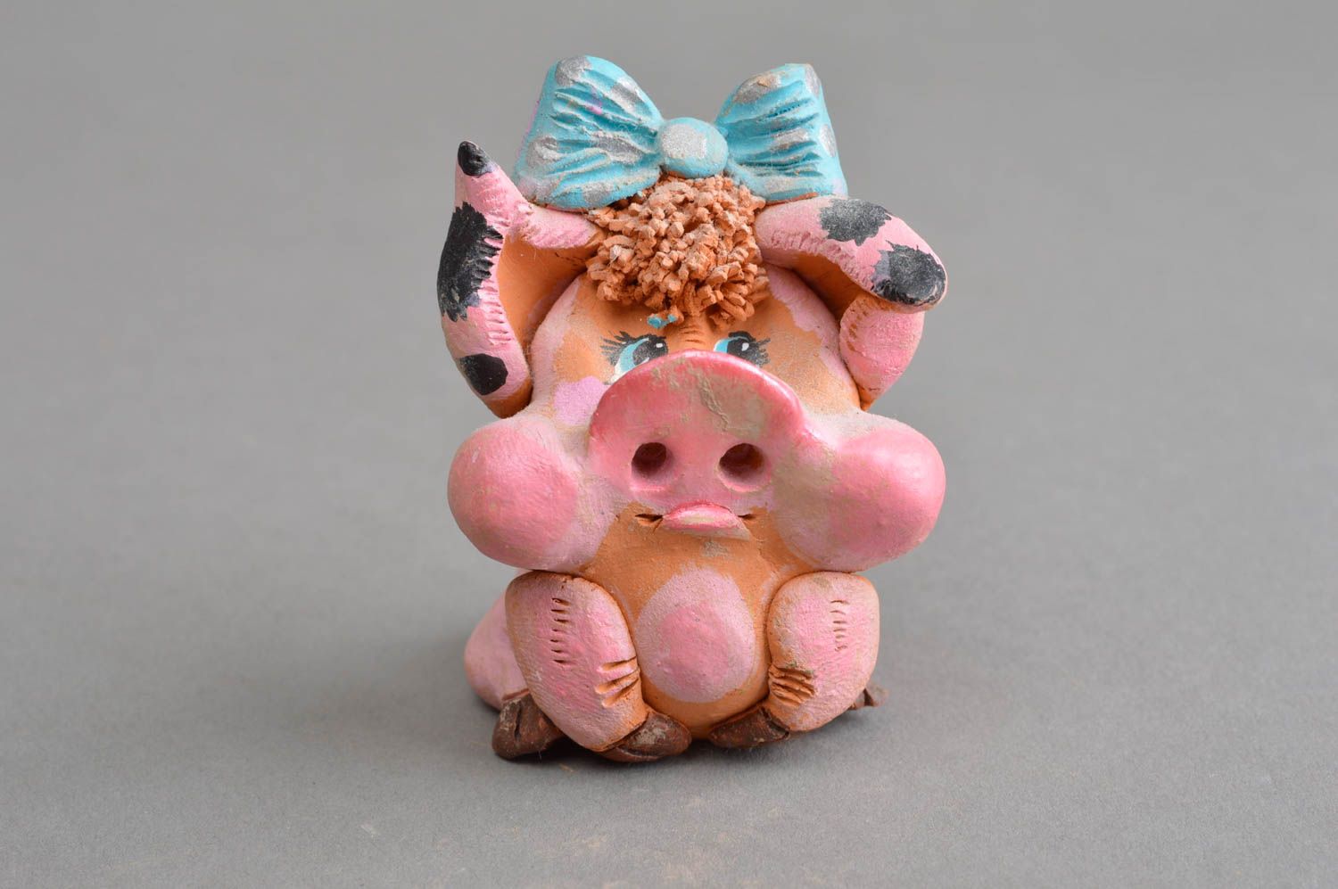 Керамический сувенир ручной работы задумчивая свинка розовая с голубым бантом фото 2