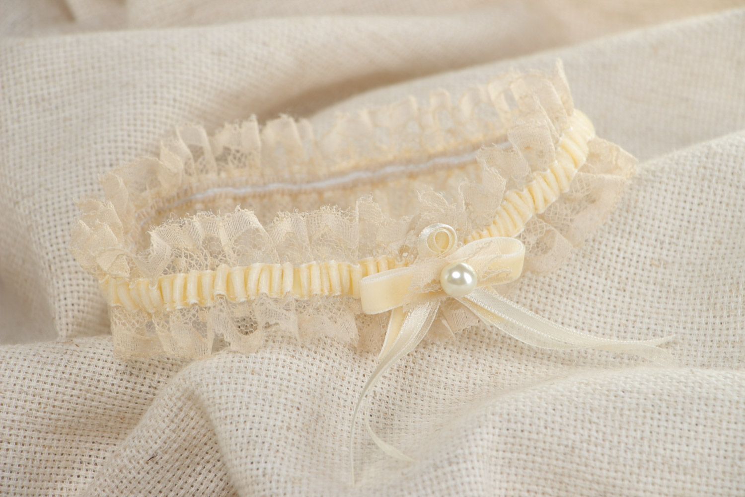 Tender thin lacy wedding bridal garter of champagne color with velor and pearls  photo 1