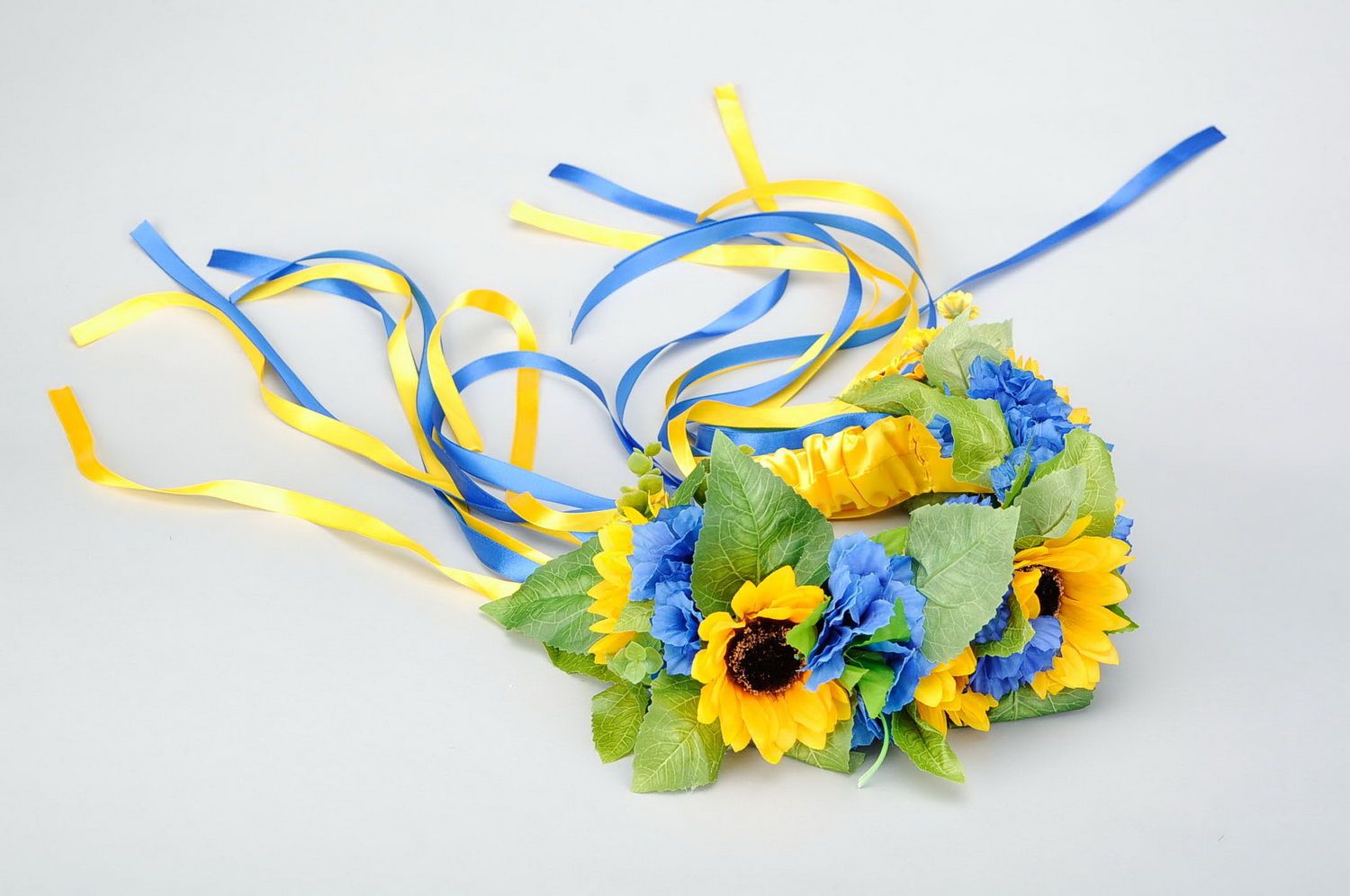 Wreath with artificial flowers and thin ribbons photo 1