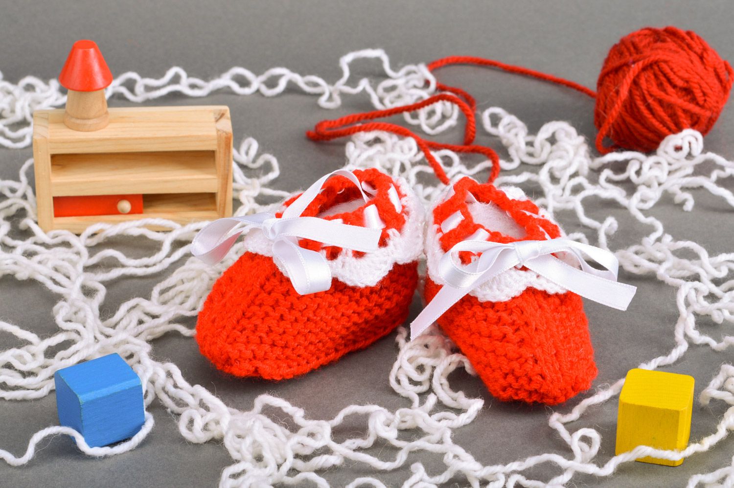 Gestrickte kleine rote Babyschuhe handmade mit Schnürung aus weißen Atlasbändern foto 1