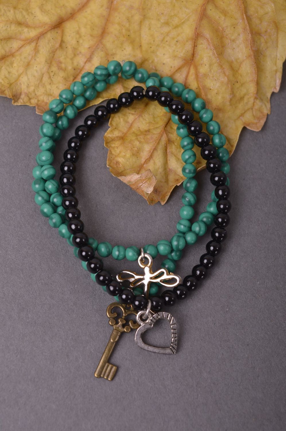 Handmade beaded set of the three-row bracelet on elastic cord with black, dark green beads and charms in butterfly heat and door key shape photo 1