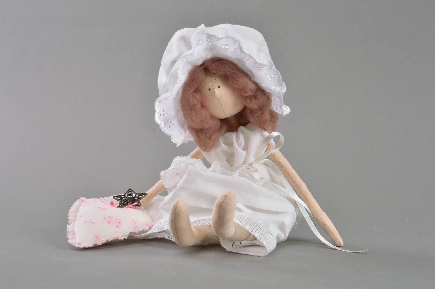 Handmade cute toy doll made of fabric in white dress and bonnet on stand photo 4