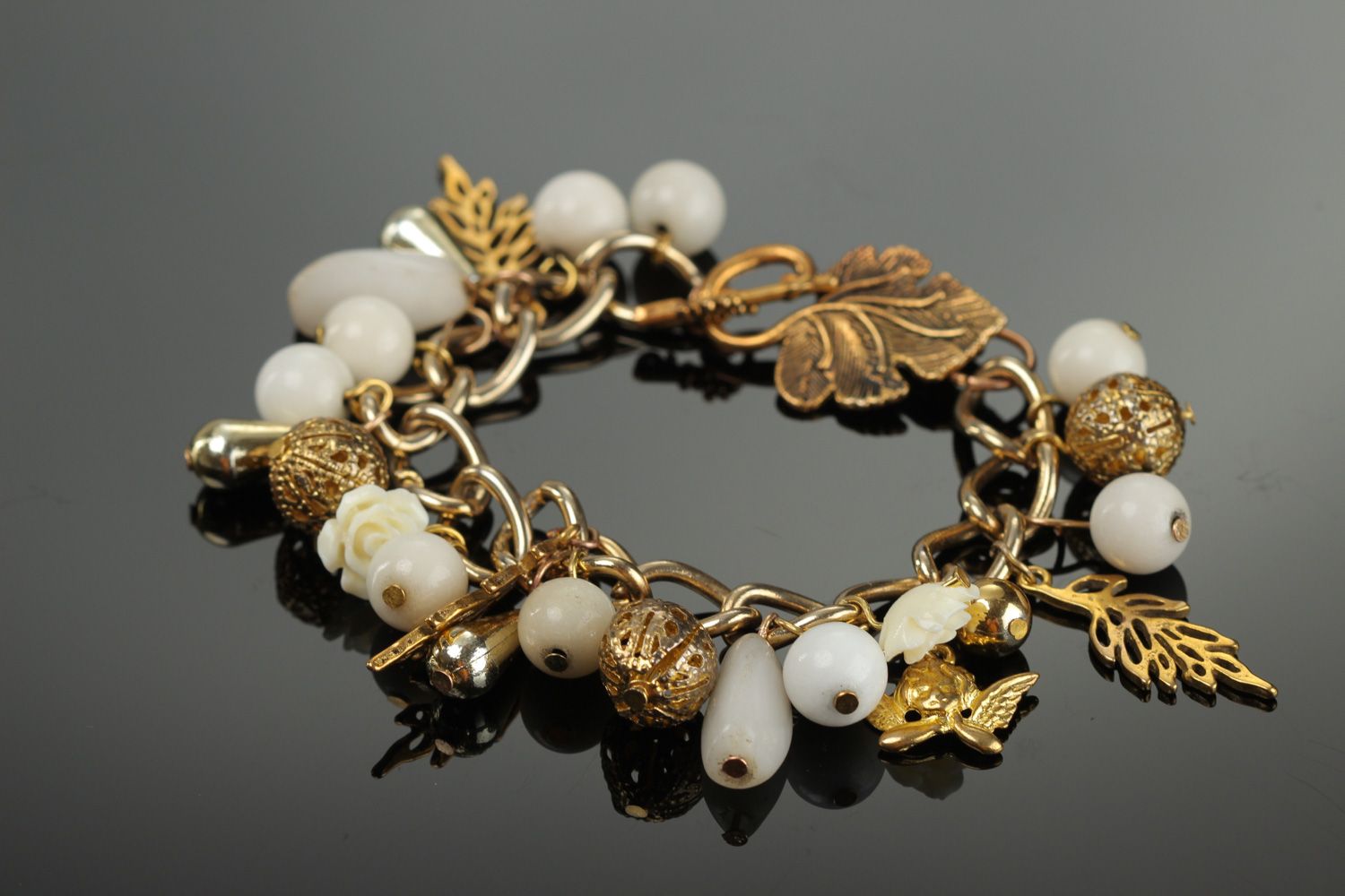 Handmade women's wrist bracelet with charms and beads of white and gold color photo 1