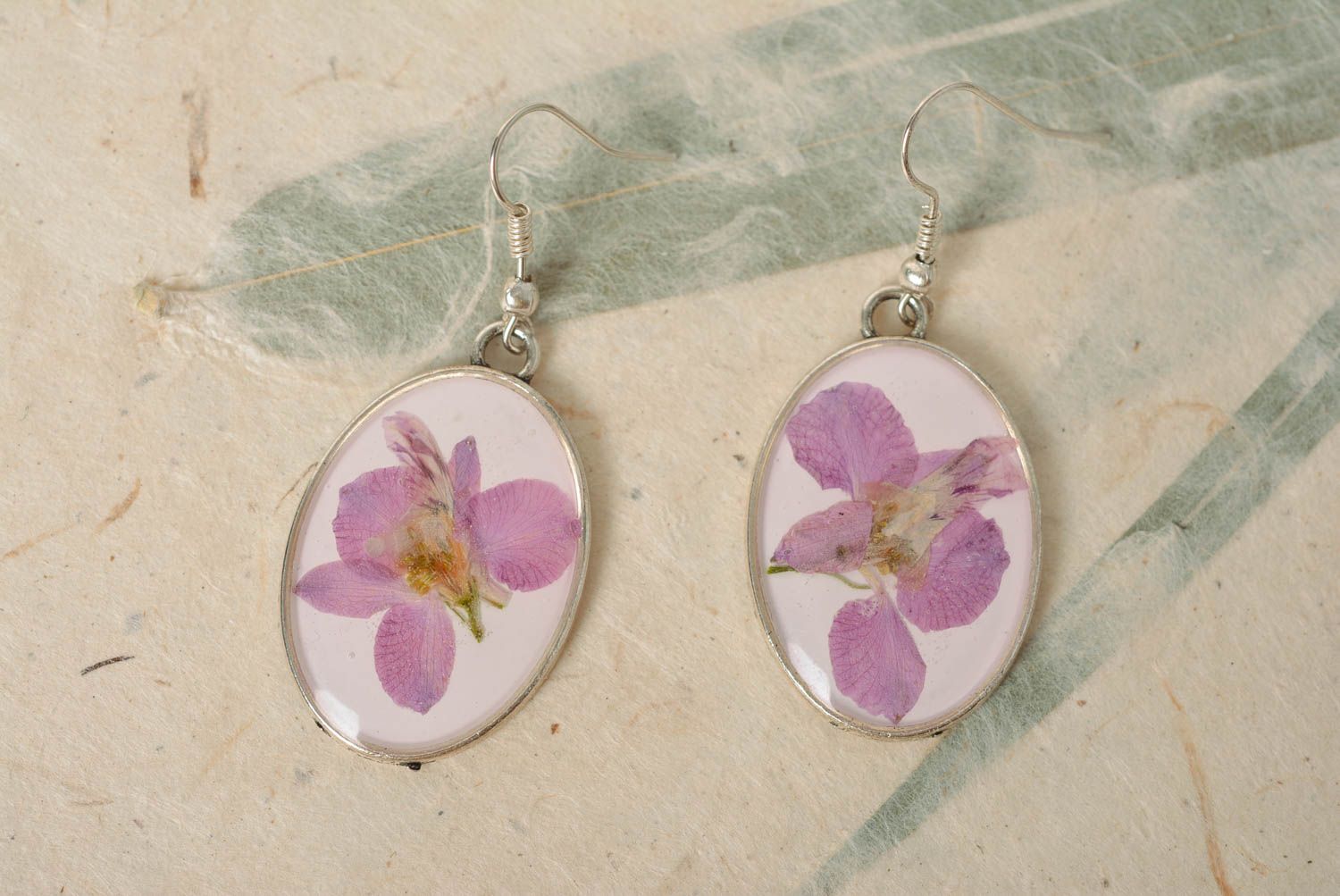 Handmade laconic oval dangle earrings with violet flowers in epoxy resin photo 1