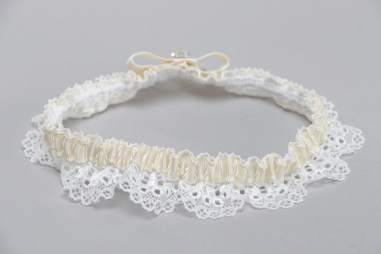 Handgemachtes weißes Strumpfband für Hochzeit aus Spitze und Ripsbändern mit Glasperle foto 4