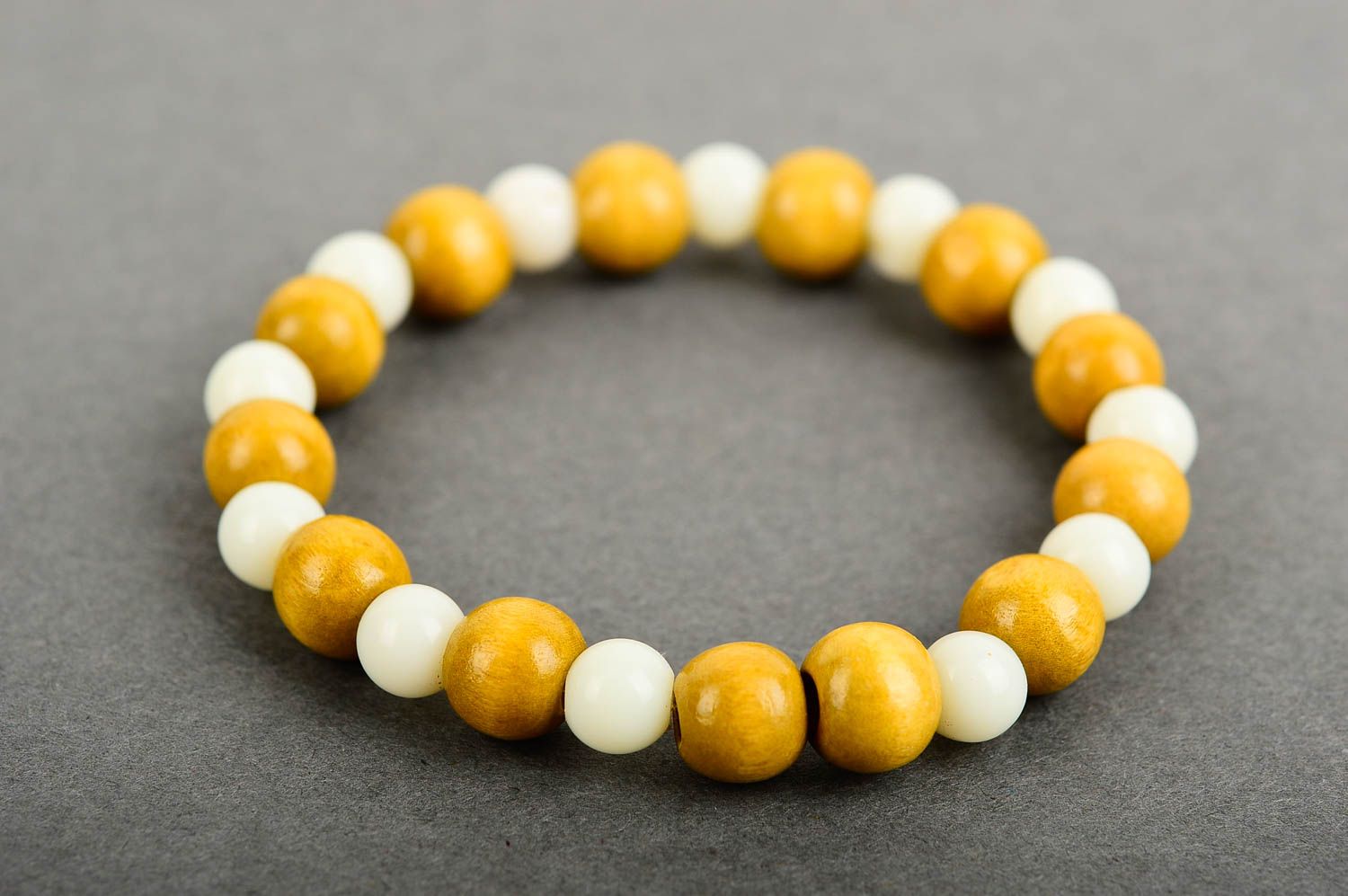 Stretchy beaded bracelet made of yellow wooden and white plastic beads photo 3