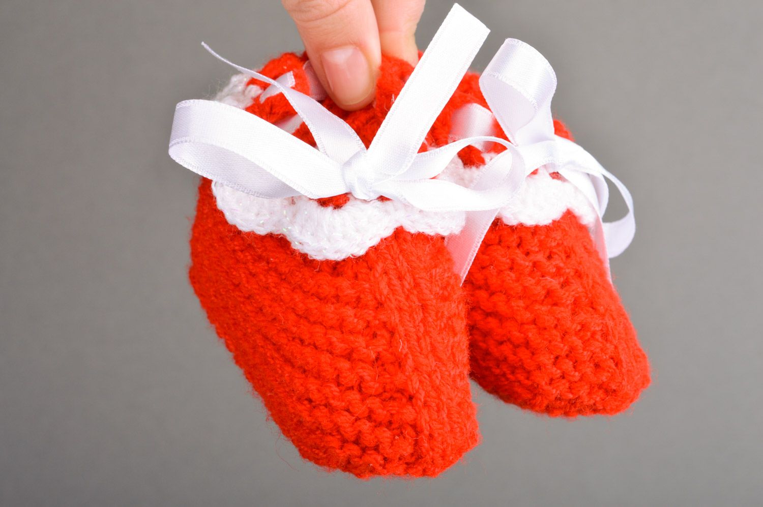 Gestrickte kleine rote Babyschuhe handmade mit Schnürung aus weißen Atlasbändern foto 3