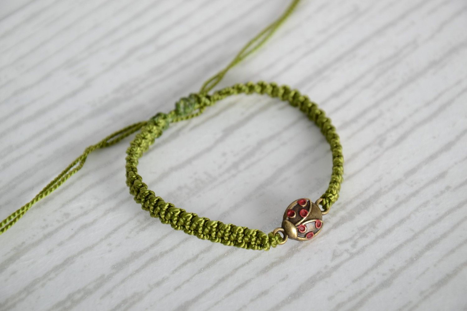Handmade woven capron thread bracelet of green color with ladybug charm photo 1
