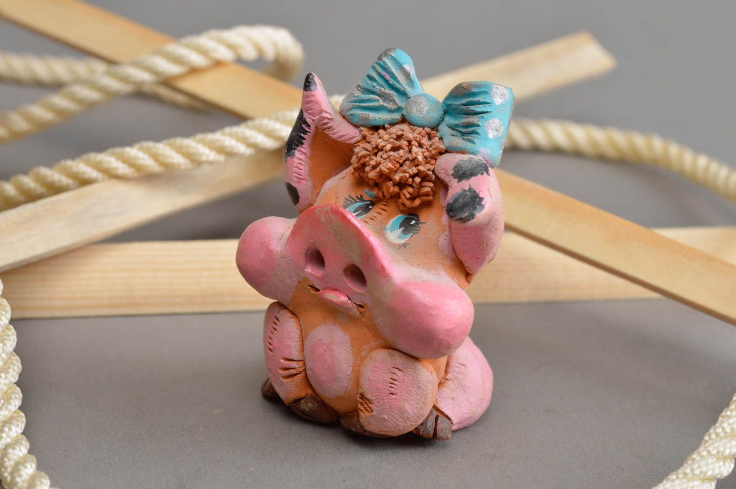 Керамический сувенир ручной работы задумчивая свинка розовая с голубым бантом фото 1