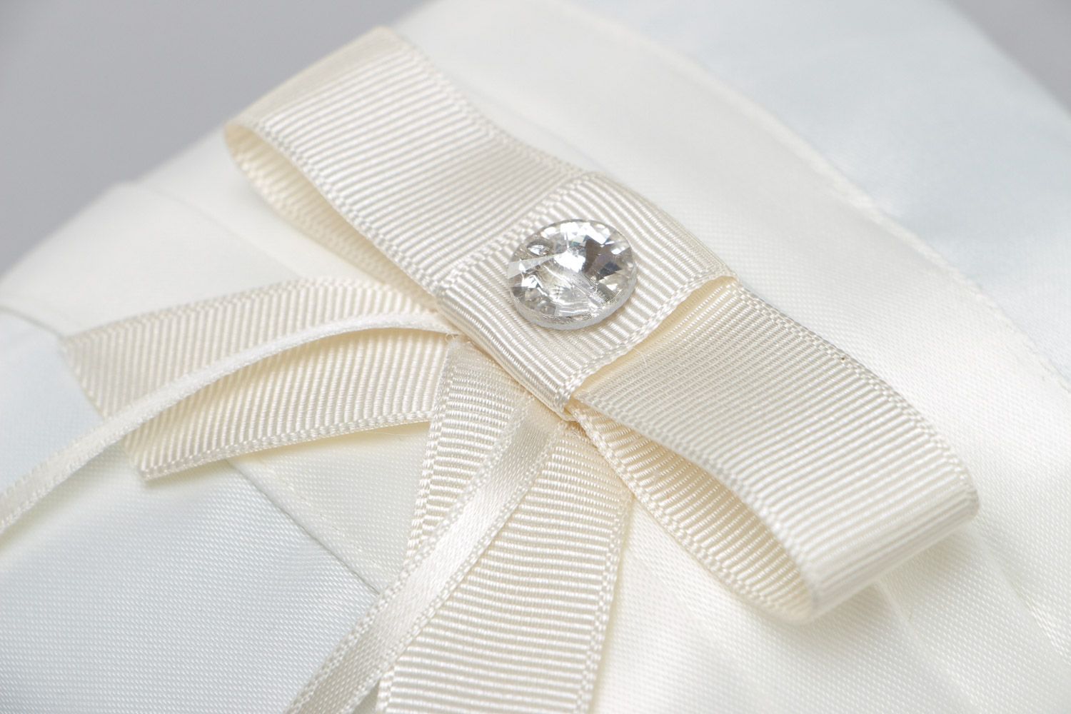 Tender handmade wedding ring pillow sewn of ivory-colored satin fabric with bow photo 4
