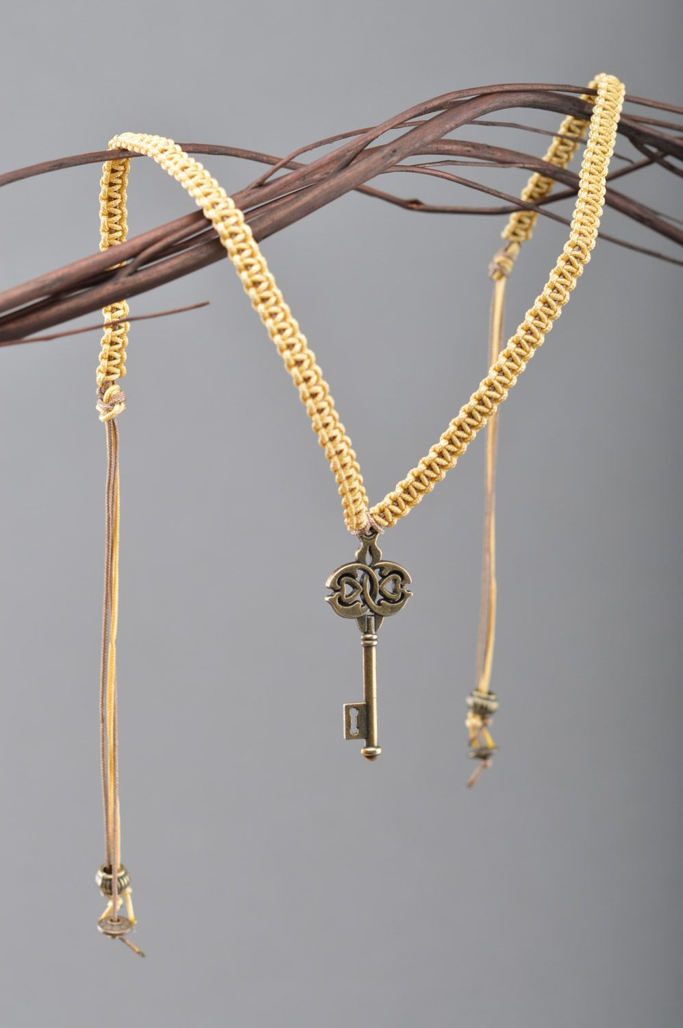 Handmade friendship wrist bracelet woven of cord with metal key-shaped charm photo 1