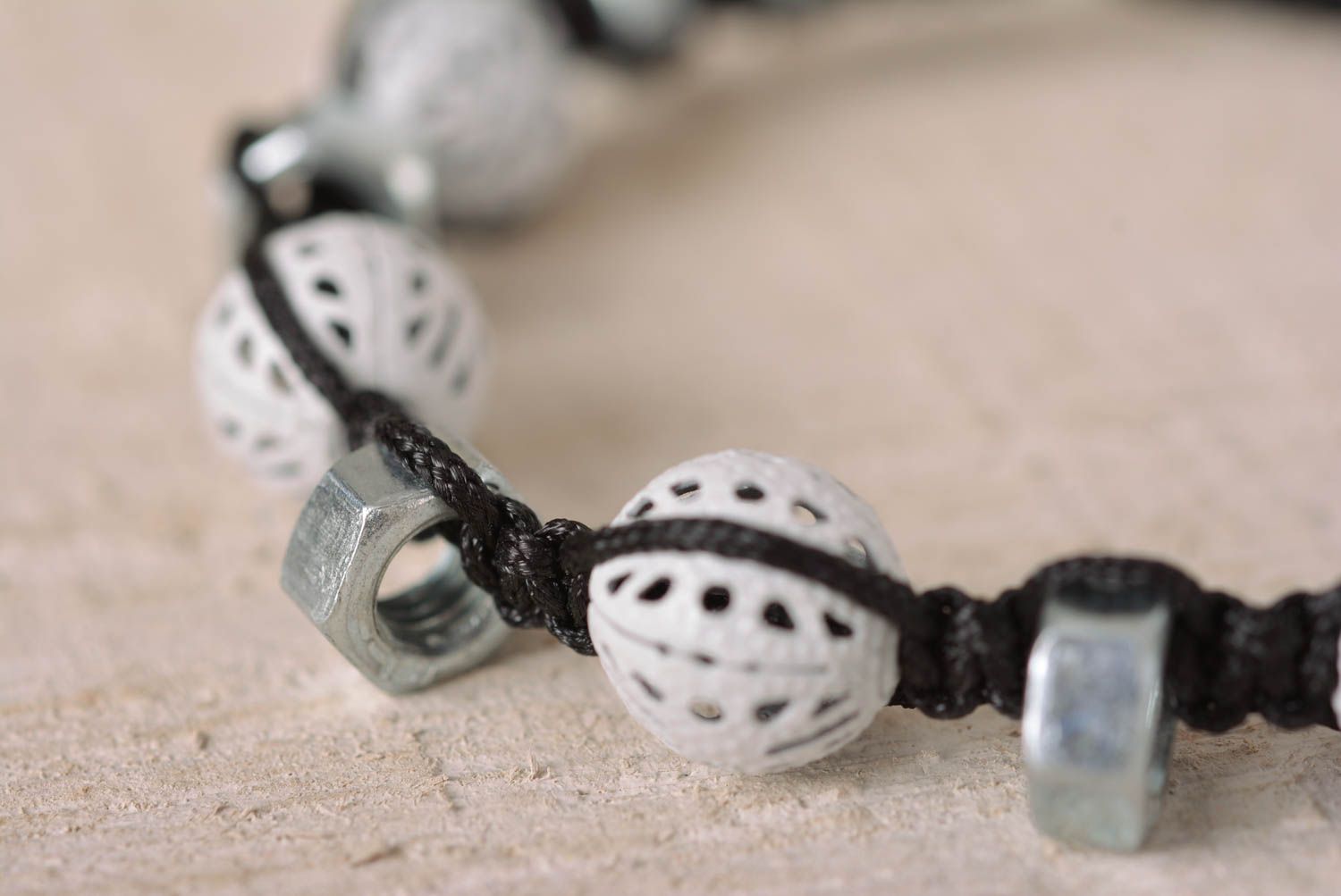 Strand black cord bracelet with white ceramic beads and female metal screws photo 2