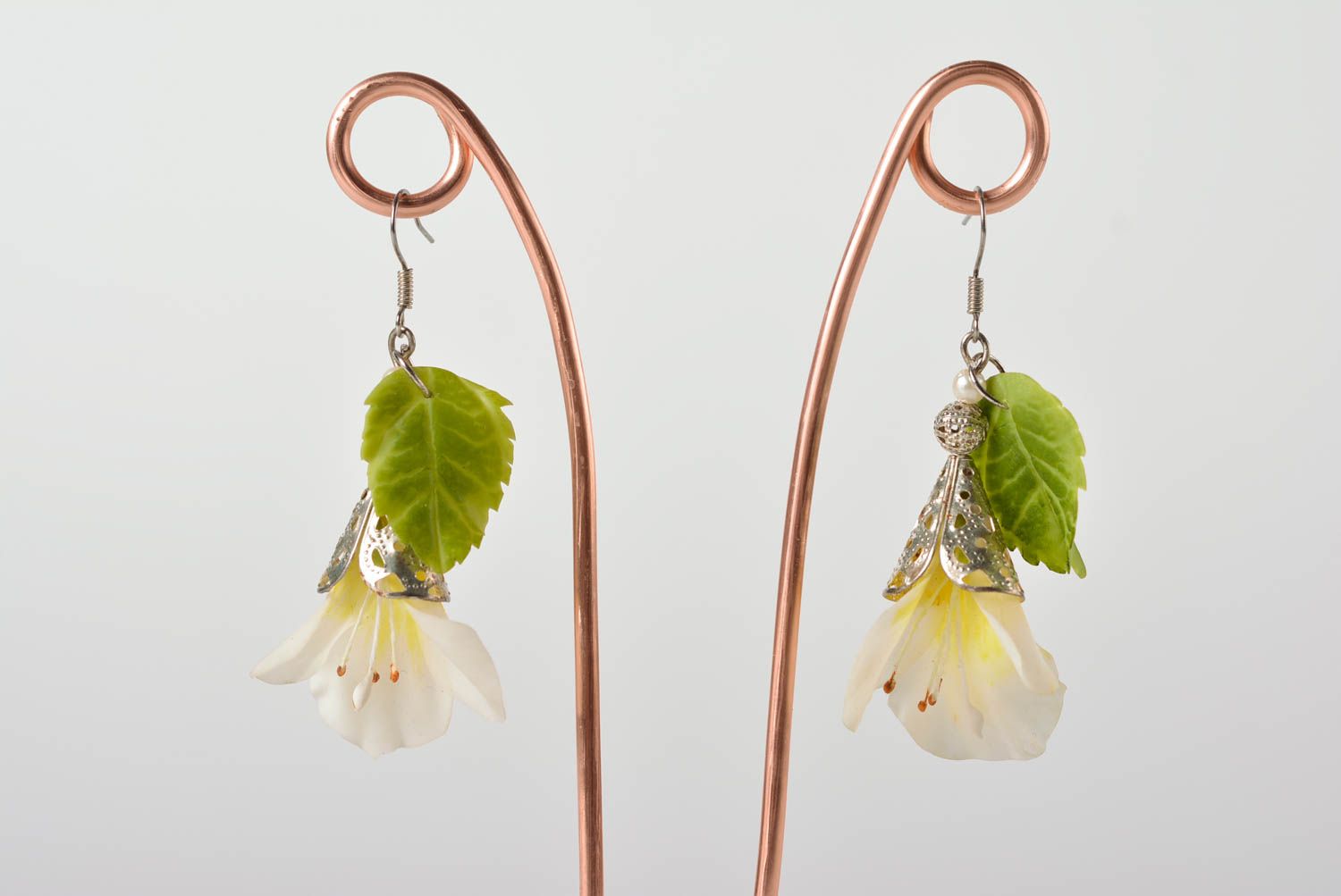 Handmade long earrings with white flowers and green leaves on metal basis photo 1