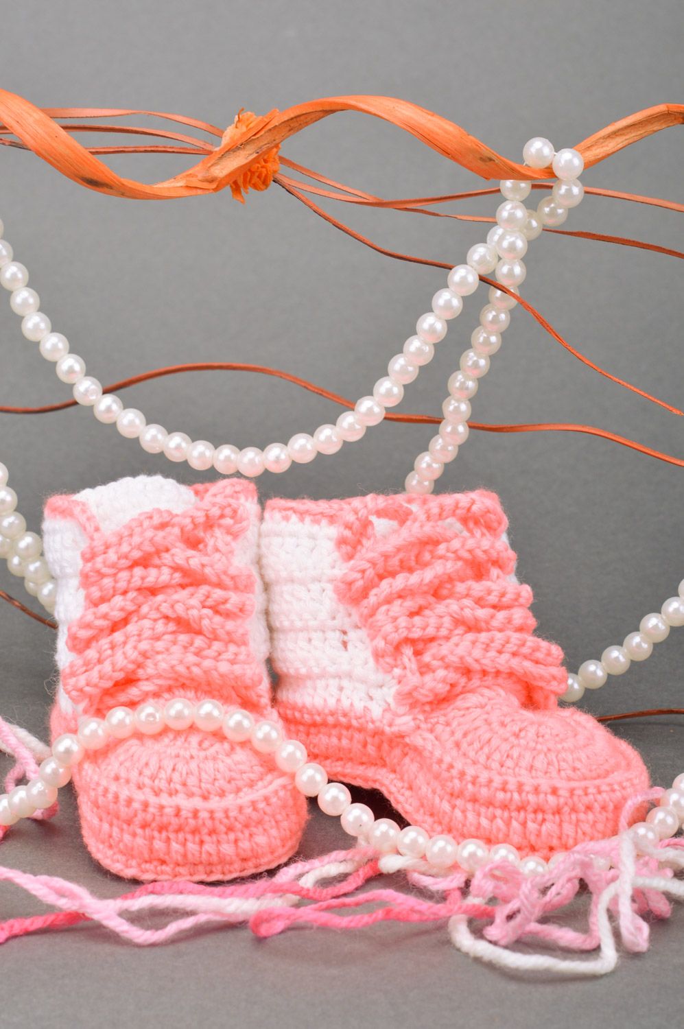 Schöne rosafarbige gehäkelte Babyschuhe mit Schuhbändern in Form der Turnschuhen foto 1