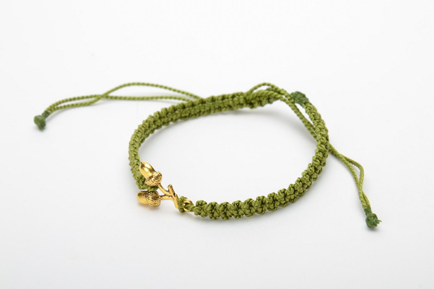 Women's handmade macrame woven thread bracelet of green color with metal charms in the shape of acorns photo 3