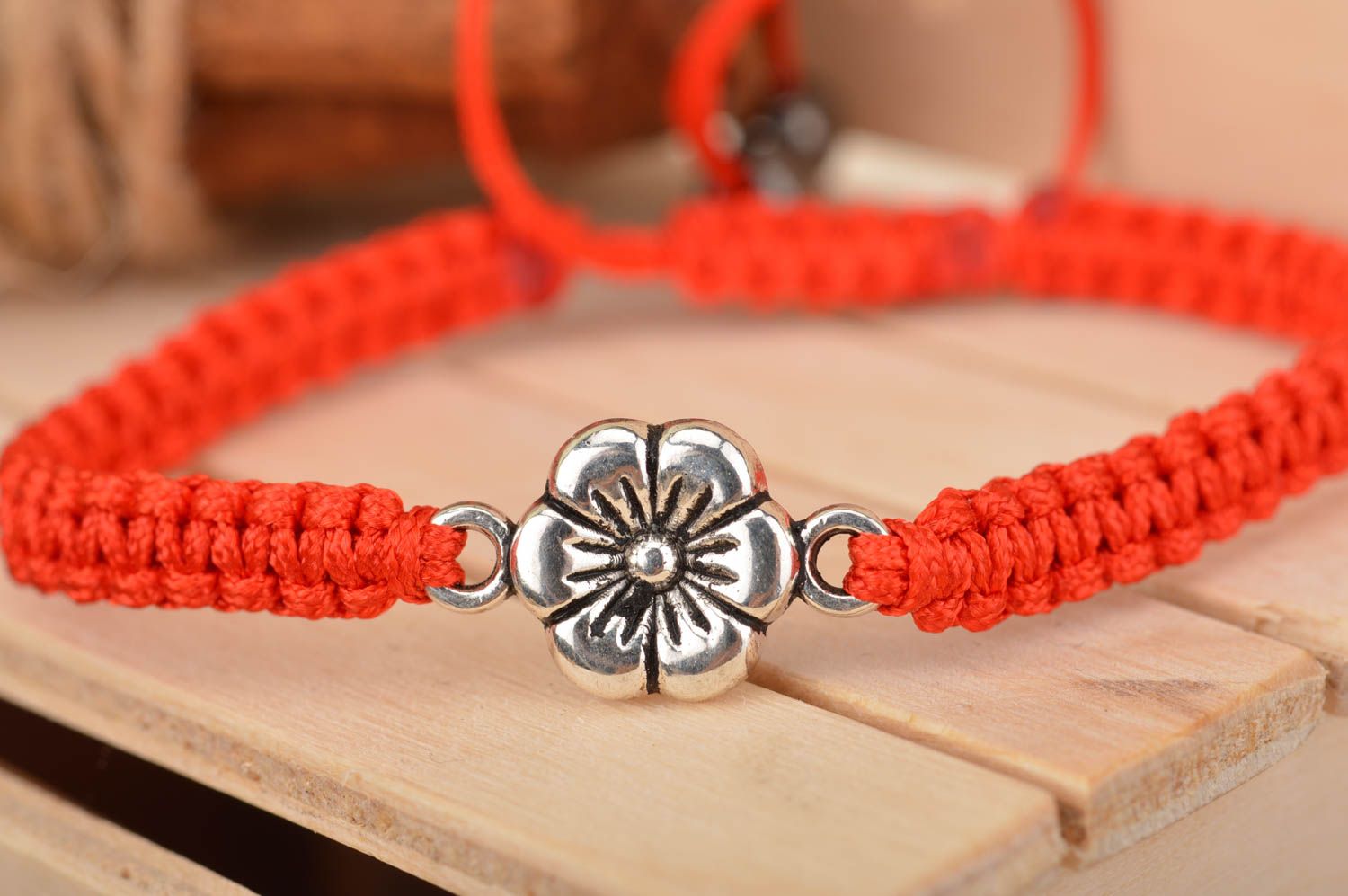 Handmade red bracelet made of silk threads with flower created of metal photo 1