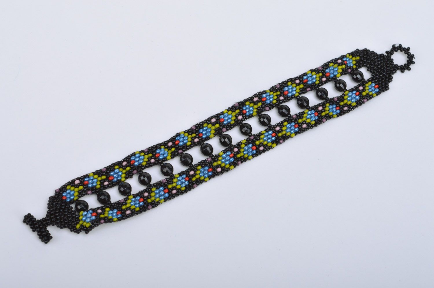 Handmade wide bracelet woven of black seed and faceted beads with flowers photo 2