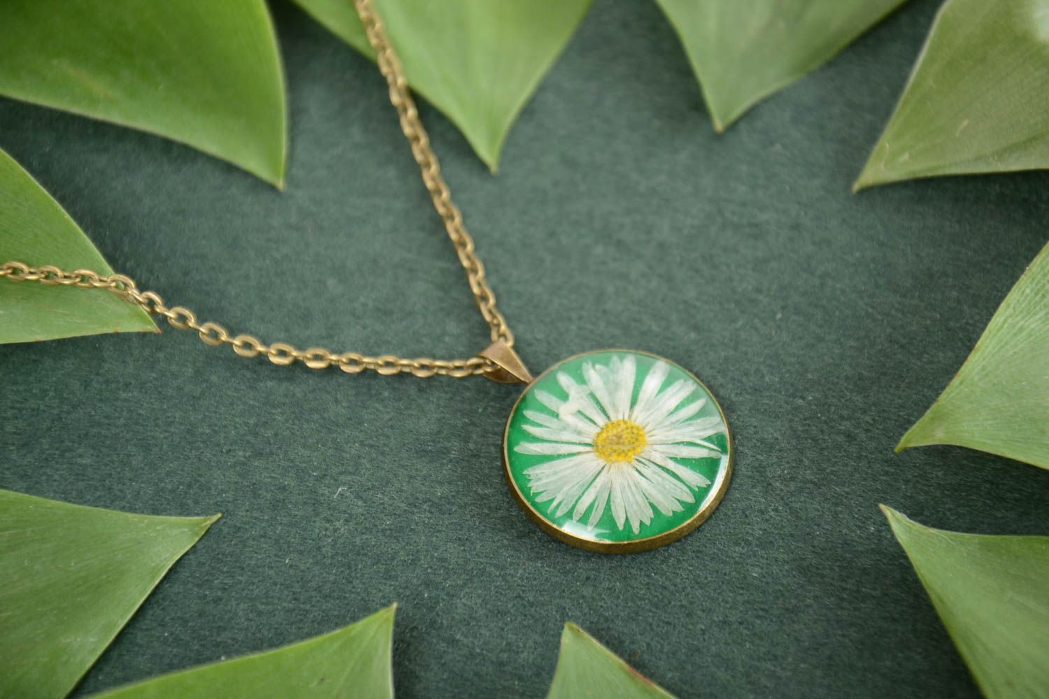 Handmade round pendant with chamomile in epoxy resin on green background photo 1