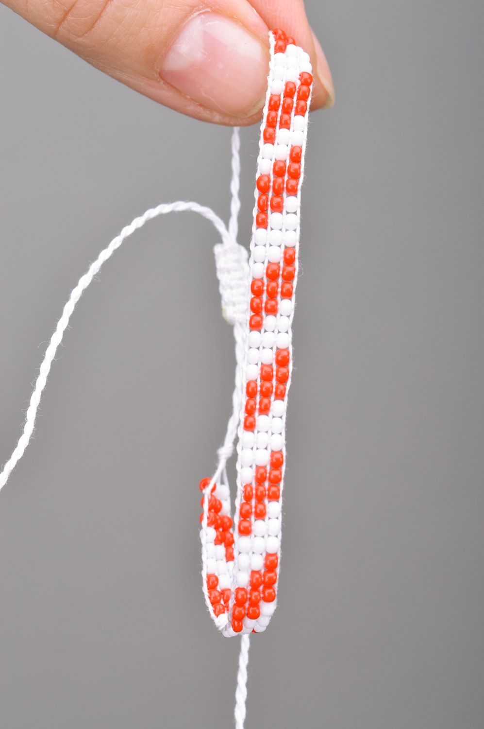 Плетеный браслет на руку из бисера ручной работы красный с белым тонкий фото 3