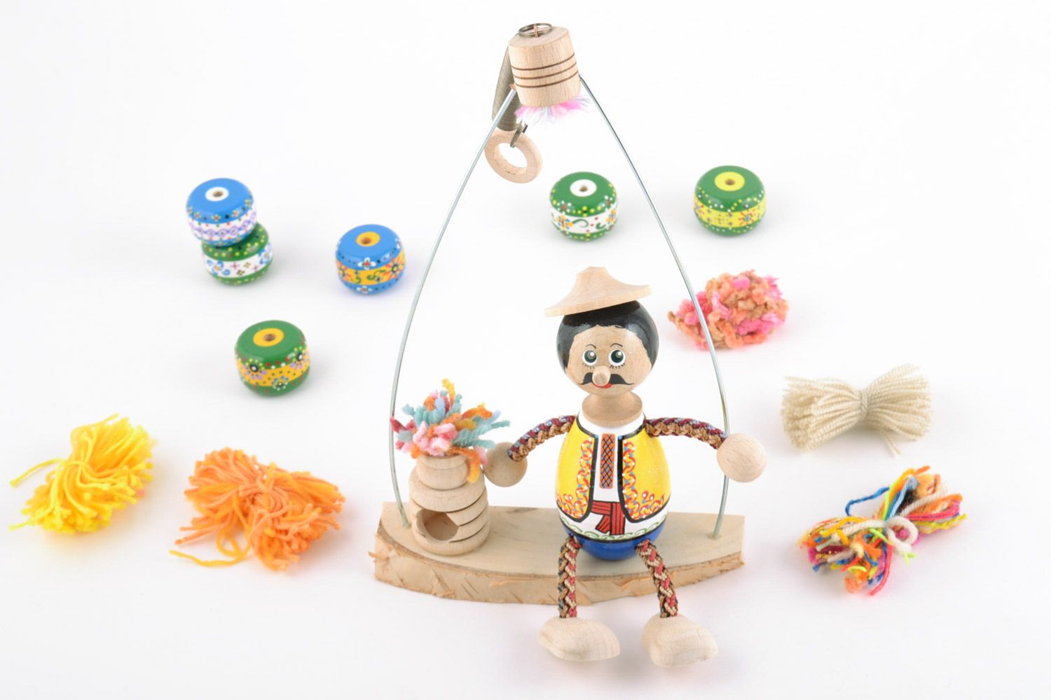 Handmade decorative wooden toy doll on a swing bench hand-decorated with paints photo 1