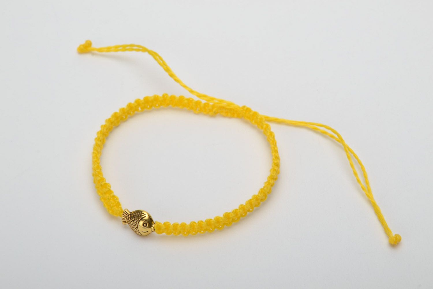 Handmade women's designer macrame woven bracelet of yellow color with metal charm in the shape of fish photo 3
