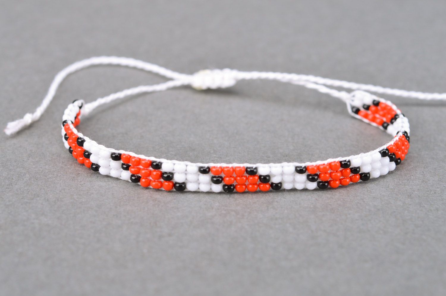 Handmade thin beaded bracelet with red and black pattern and ties photo 2