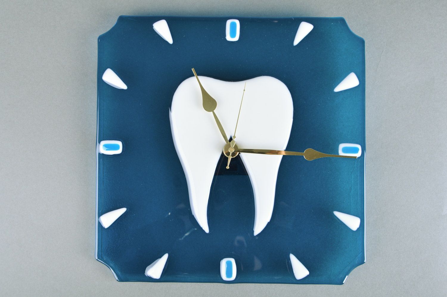 Reloj de cristal en técnica de vitrofusión artesanal diente en fondo azul para estomatología foto 2