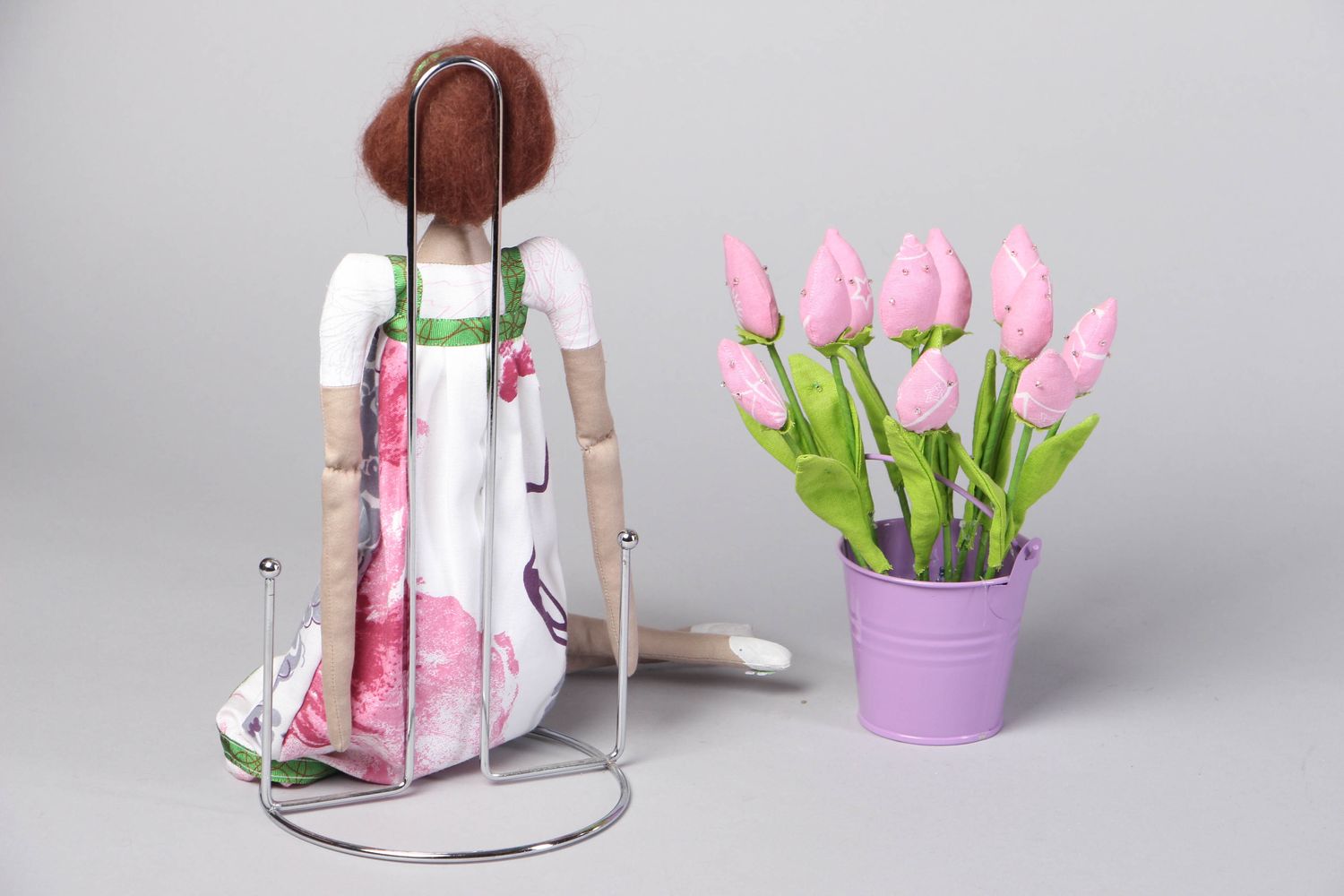 Muñeca de tela artesanal en soporte con flores foto 3