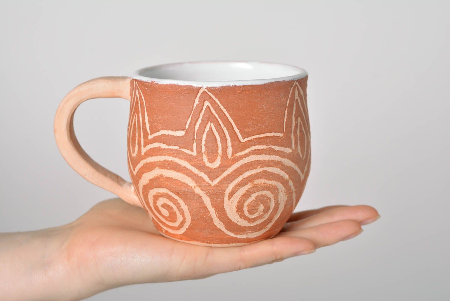 Rustic clay cup in white and brown color with handle and cave drawings photo 4