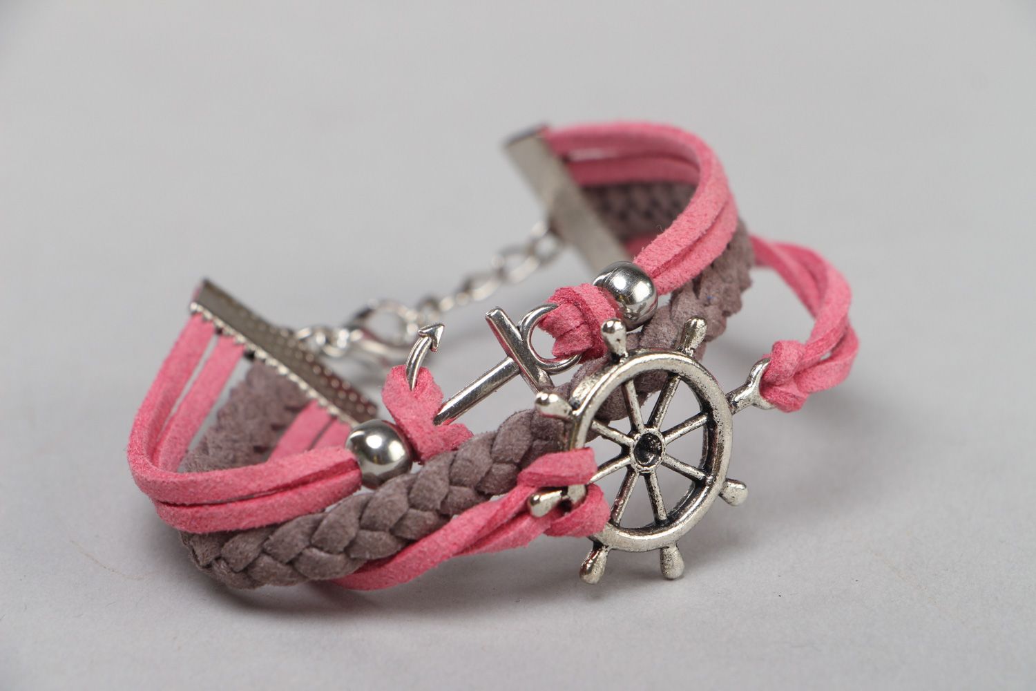 Pulsera artesanal de gamuza artificial trenzada de colores rosado y gris con rueda de timón foto 1