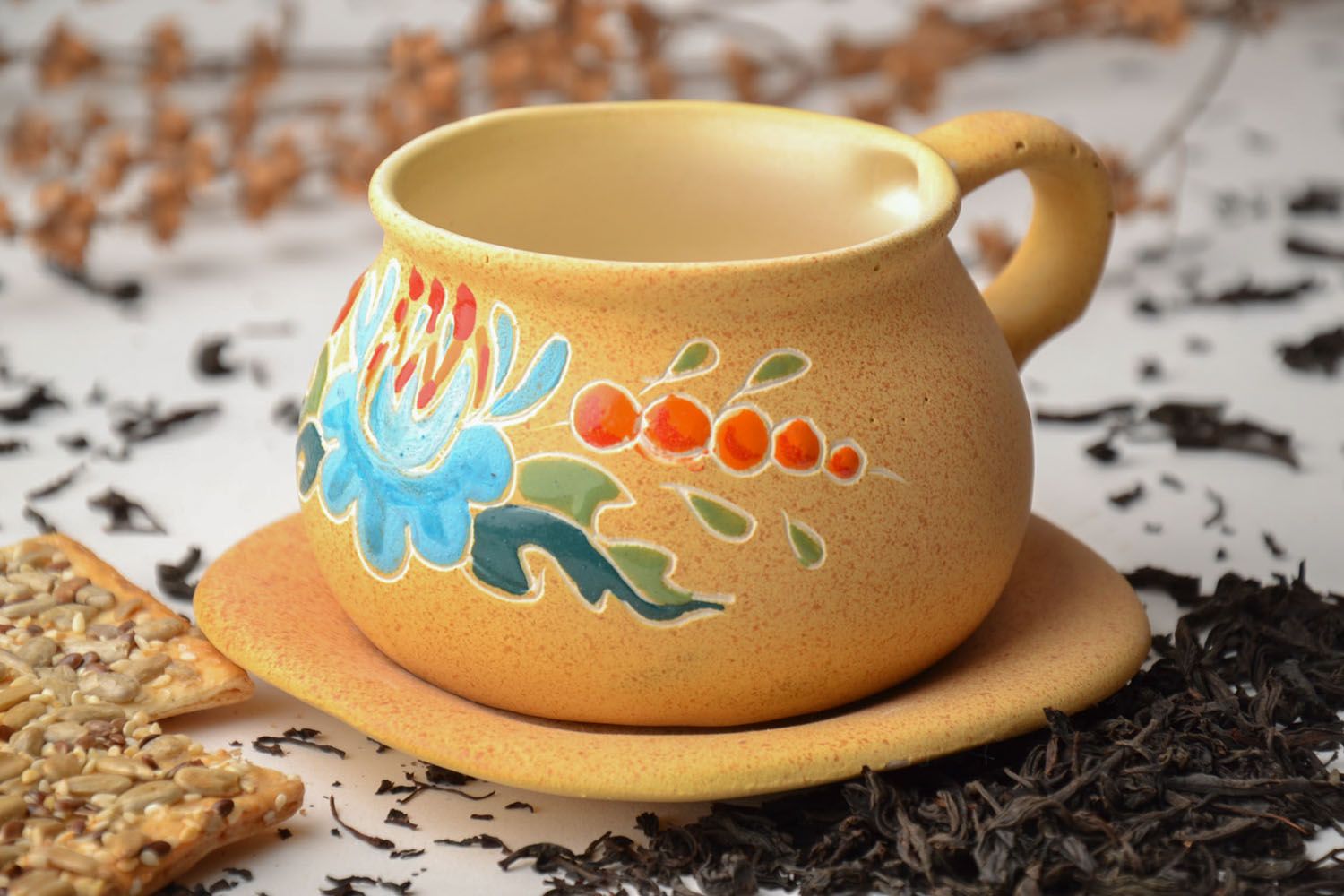 Art ceramic teacup with floral pattern in light yellow color with blue flower saucer and handle photo 1