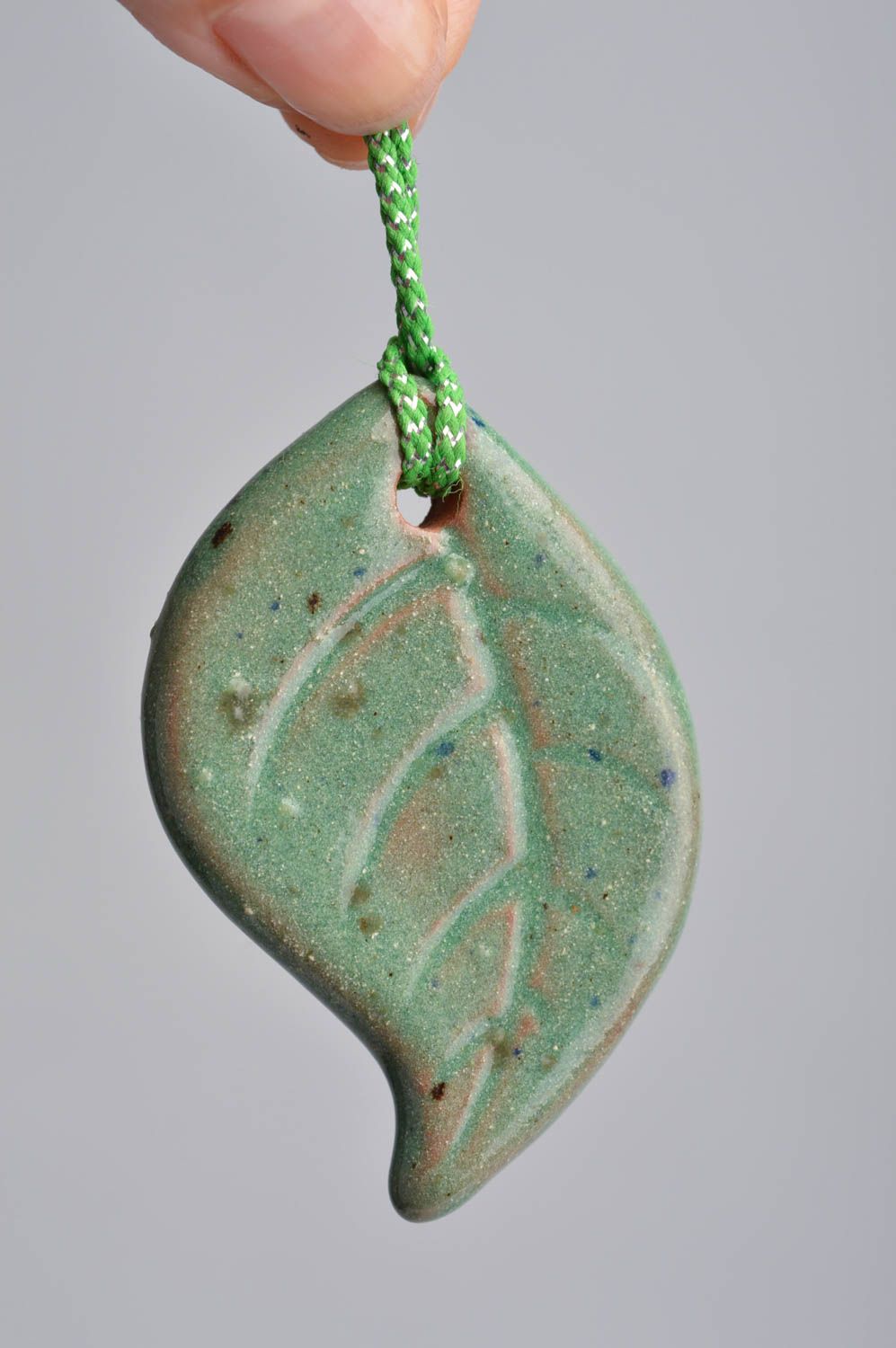 Handmade ceramic small pendant in the shape of light green leaf on a cord photo 3