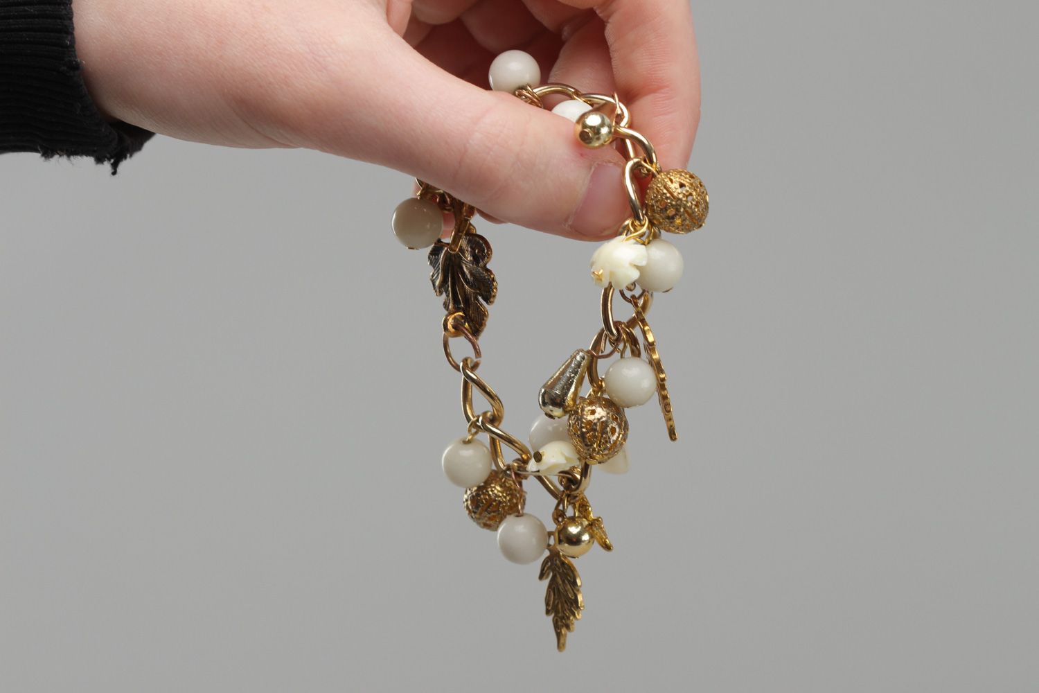 Handmade women's wrist bracelet with charms and beads of white and gold color photo 5