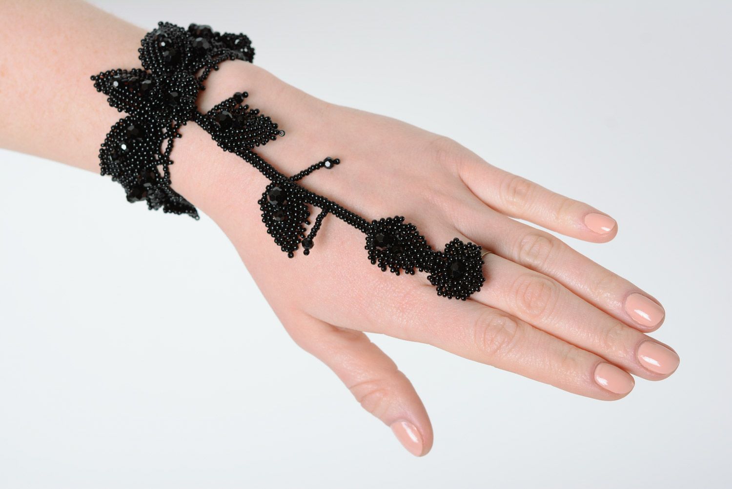 Schwarzes originelles handgemachtes Slave Armband aus Glasperlen auf Finger mit Blättern foto 1