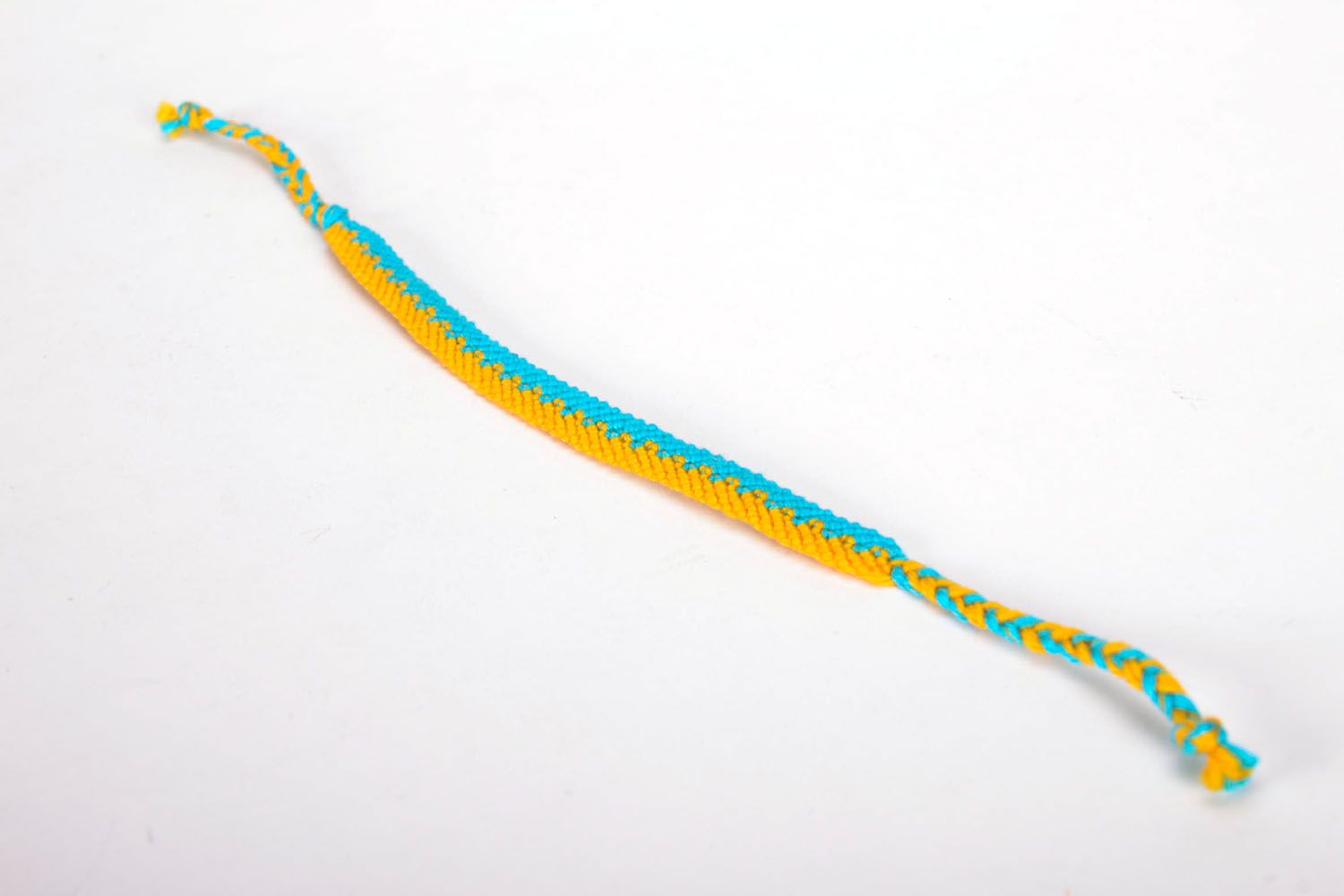 Pulsera artesanal de hilos amarillos y azules para mano foto 2