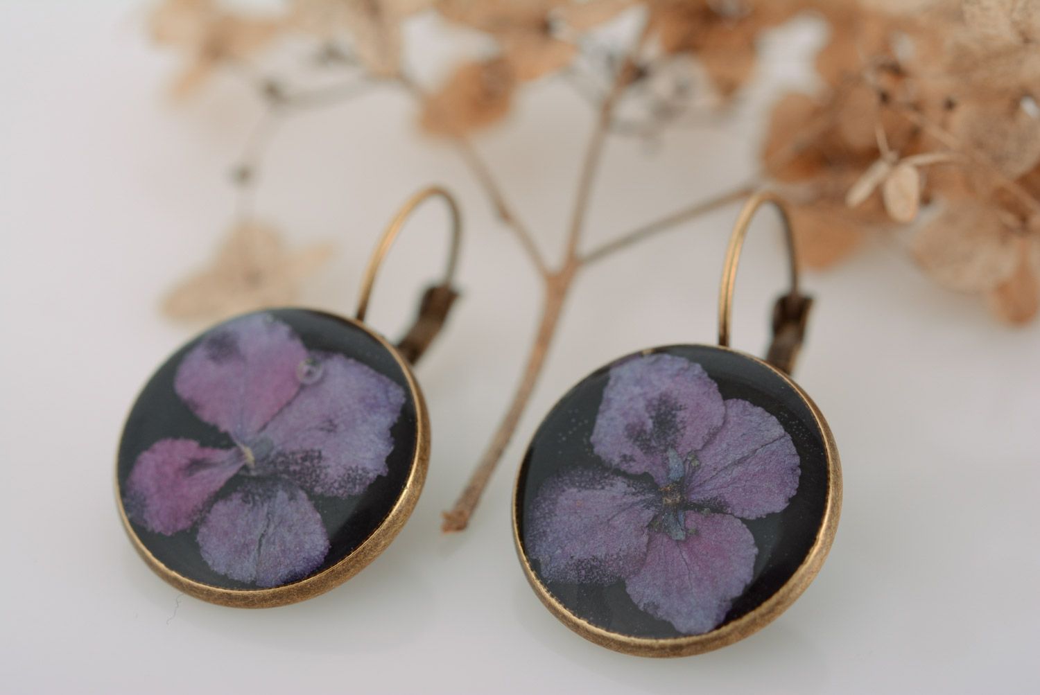 Homemade round black dangle earrings with violet flowers in epoxy resin photo 1