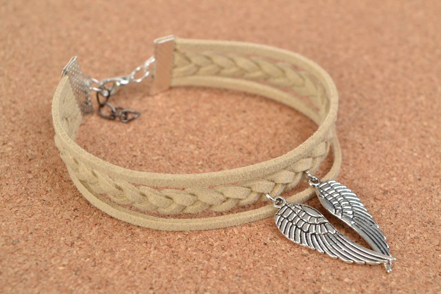 Beige handmade woven suede cord bracelet with charm in the shape of wings photo 1